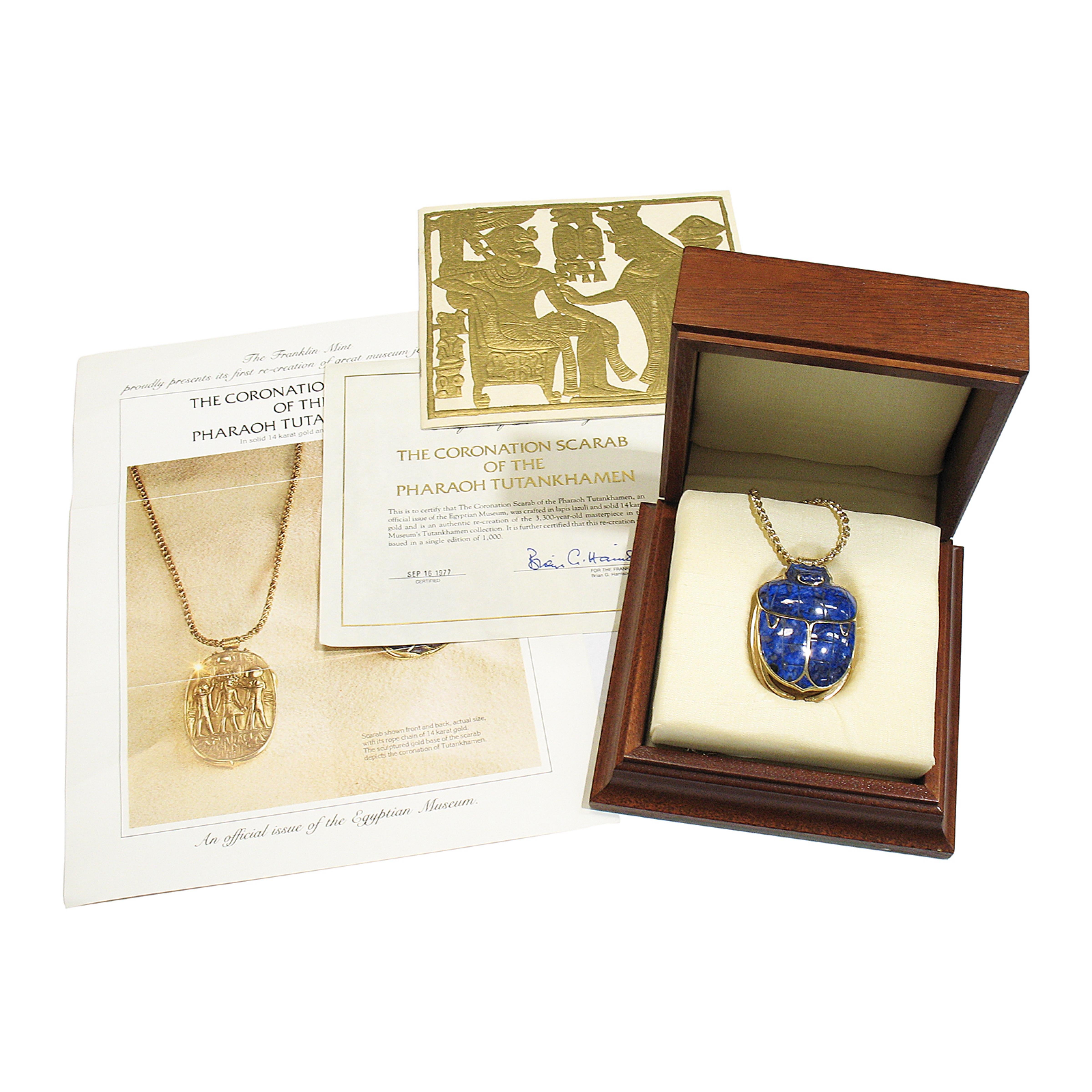 Cette grande pièce d'apparat de la Franklin Mint présente la première recréation d'un grand bijou de musée, le scarabée du couronnement du pharaon Toutankhamon, un grand pendentif en or massif 14 carats et lapis-lazuli et une chaîne à maillons de