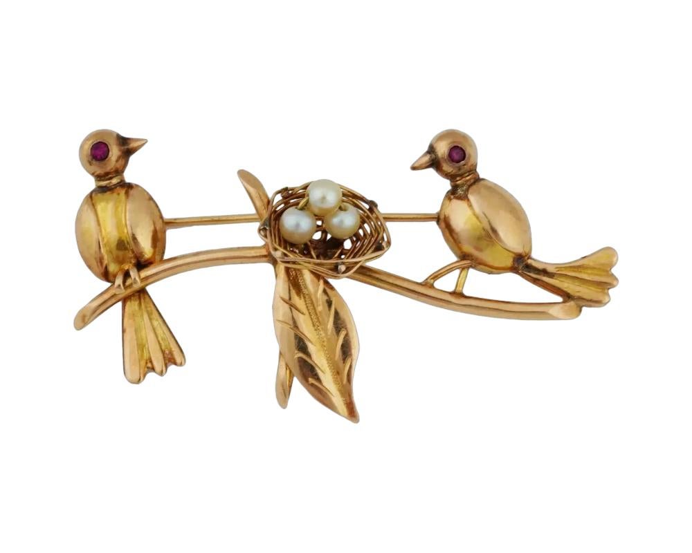 A vintage 14K Yellow Gold figural brooch. The brooch is made in a figural design representing a pair of birds seated near a nest with egg made of natural pearls. The birds are adorned with Ruby stone eyes. Unmarked. Total weight: 6.2 g. Vintage and