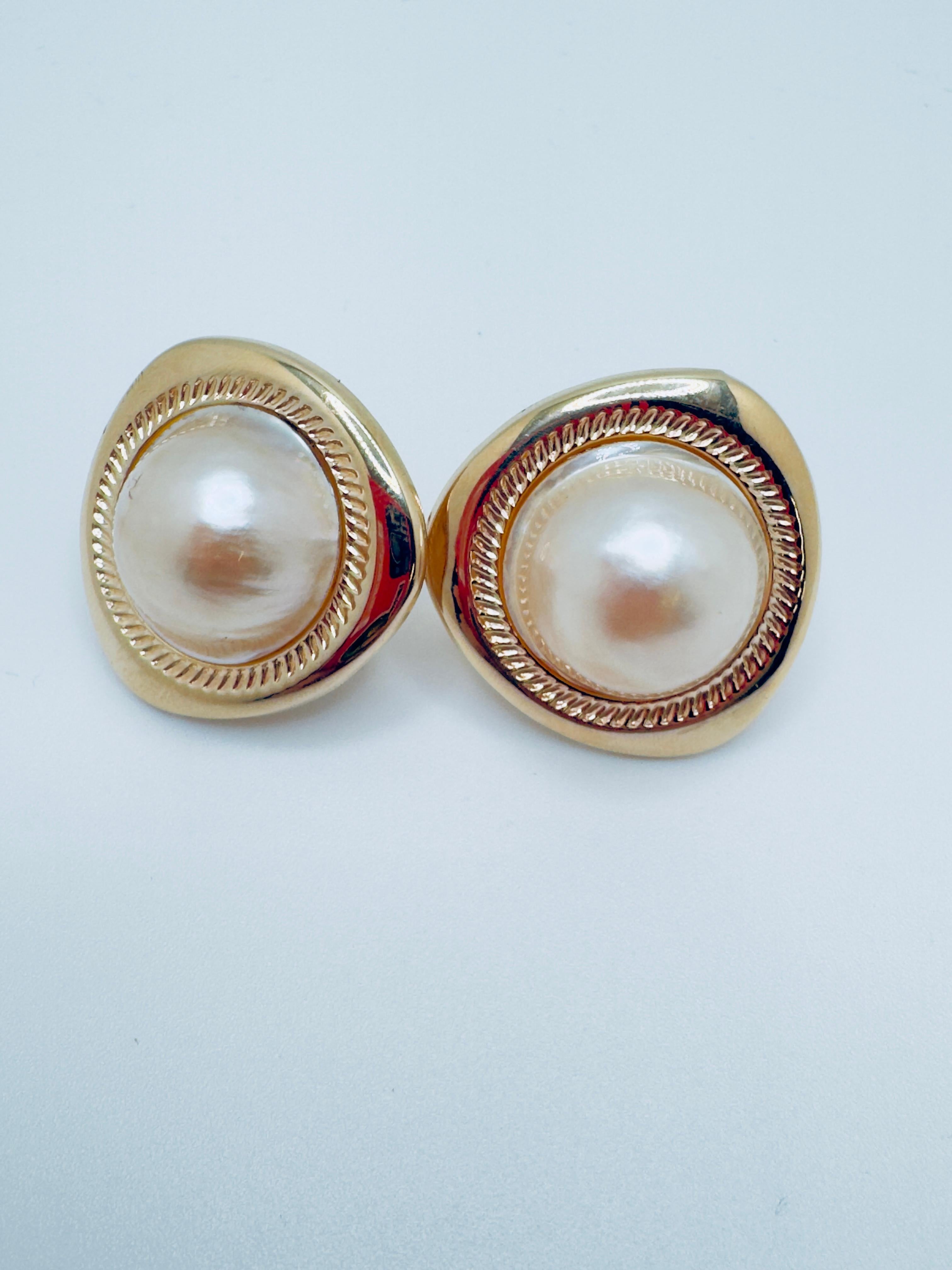 These elegant 14K gold earrings feature luxurious Mabe pearls, each measuring approximately 18mm in diameter with a soft, cream-white hue that radiates timeless sophistication. The earrings are designed with an omega back closure, ensuring a secure