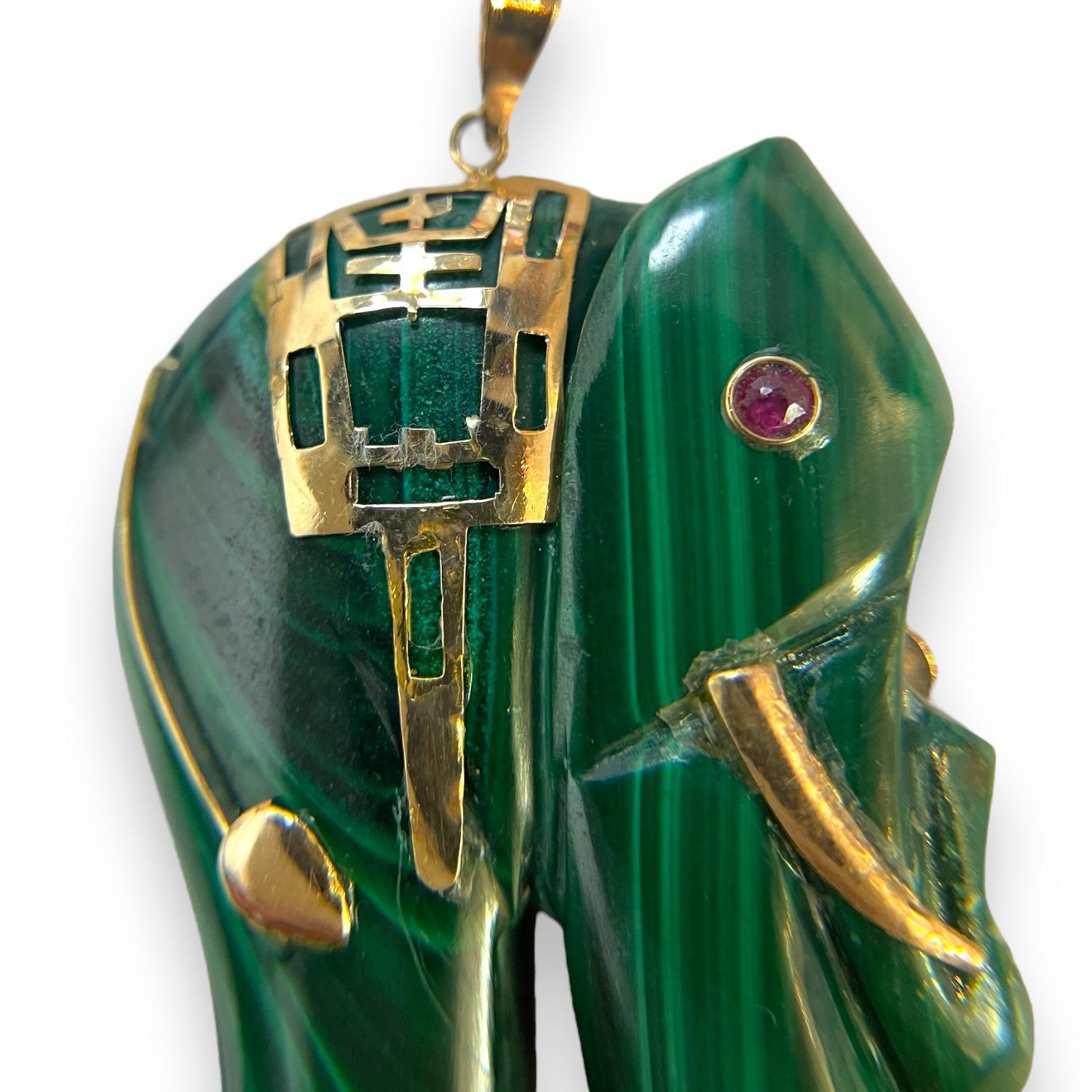 Un ciondolo affascinante con un elefante di malachite splendidamente intagliato e impreziosito da accenti in oro giallo 14K. Il vibrante occhio di rubino aggiunge un tocco di eleganza e fascino, rendendo questo pezzo un simbolo unico di forza e