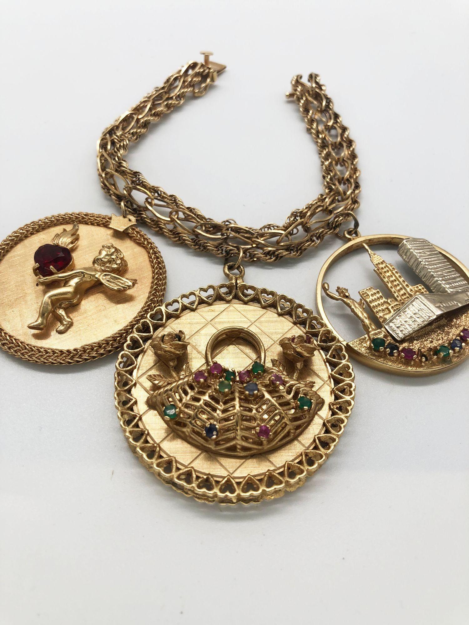 Charming mid-century ladies' charm bracelet featuring 3 charms with room to add more. All 3 have 14K gold markings on them as well as the substantial gold chain. Charms feature a cherub holding a burning jewel heart, a basket of roses, and a New