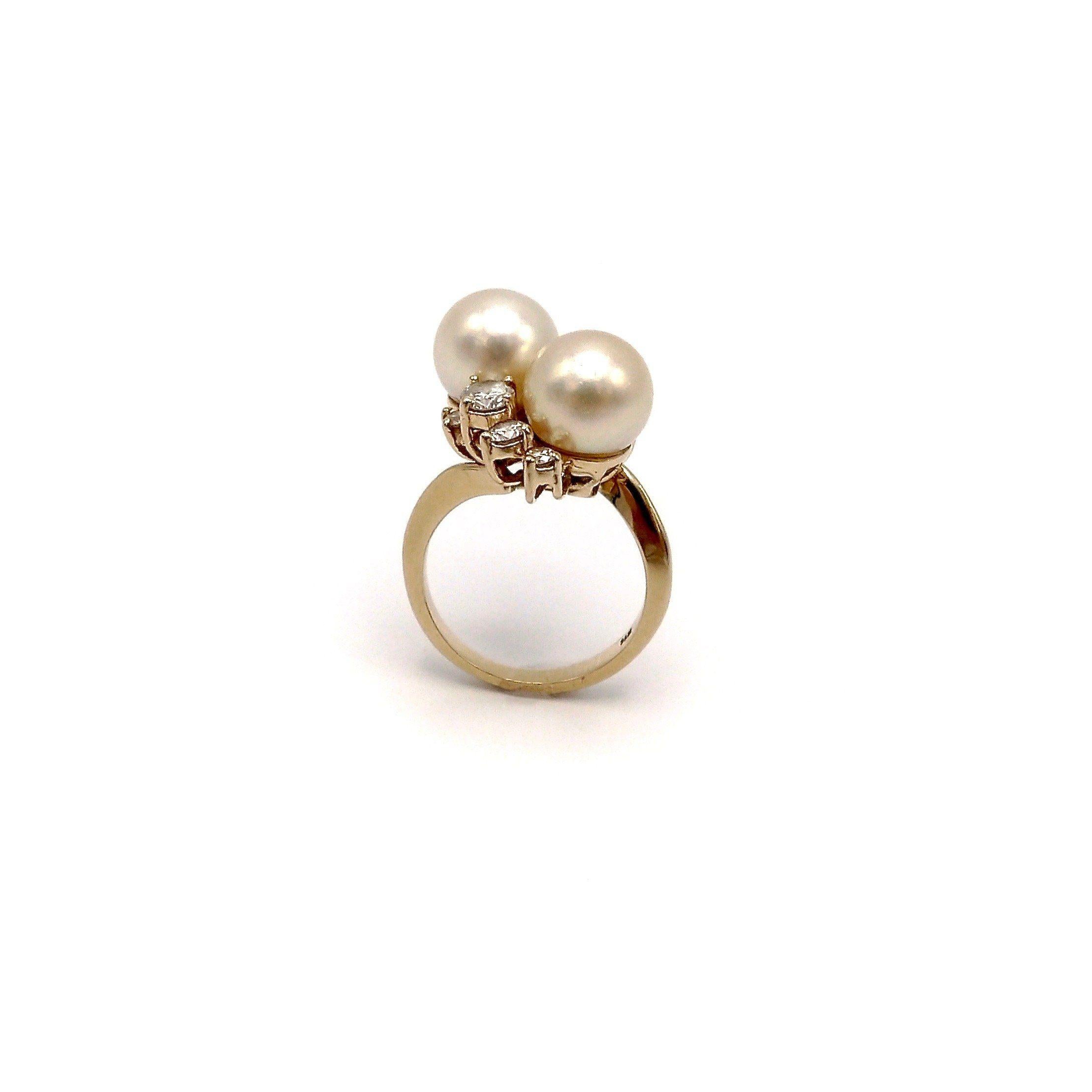 This stunning bypass ring features two cultured pearls and eight diamonds. The ring is made in the 1950's and has a classic and elegant style. Bypass rings such as this one were popularized in the Victorian era and quickly became the ideal ring for
