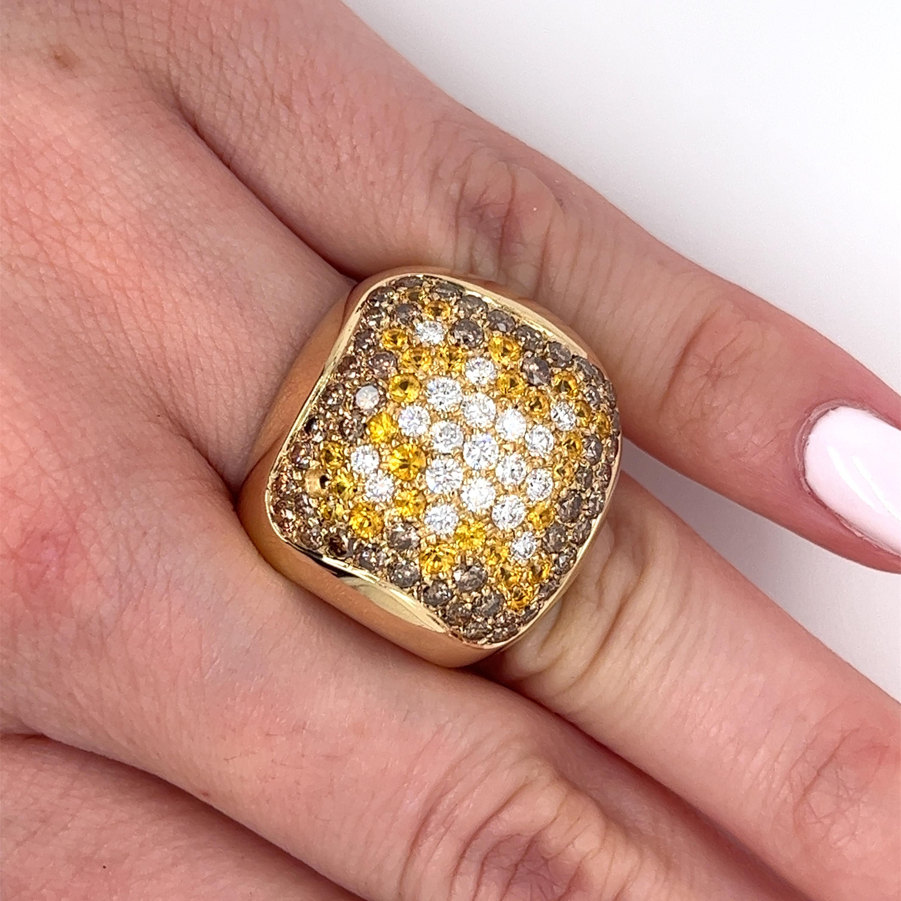 This ring features a cluster of round brilliant cut white and brown diamonds, complemented by yellow sapphires. The dome-shaped design is set in 14k yellow gold with a curved open ring shank. All natural, mined gemstones and set in 14 karat solid