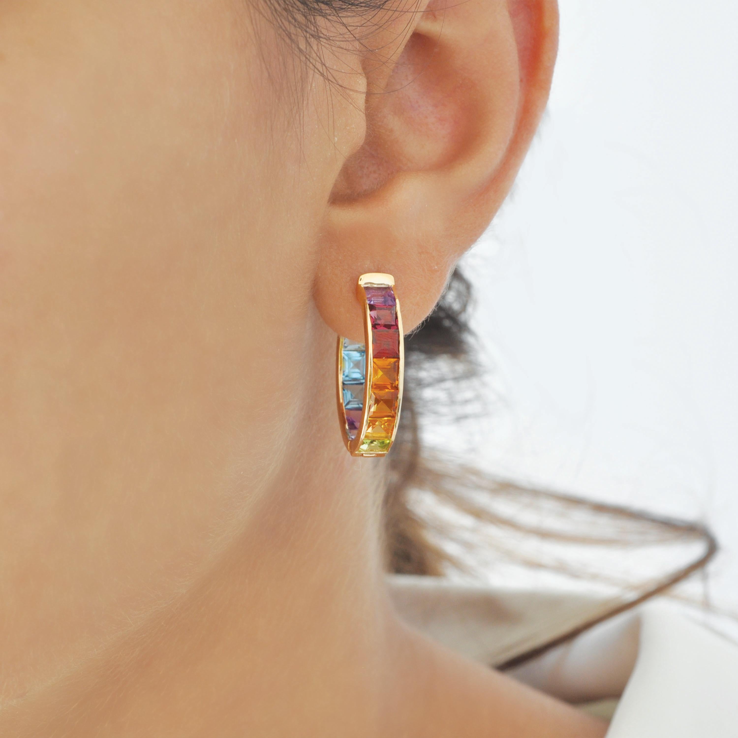 Presenting the 14 karat yellow gold multi-color rainbow channel set hoop pride earrings – a blend of contemporary elegance with playful charm. These earrings feature a sleek hoop design adorned with carefully arranged multicolored gemstones set
