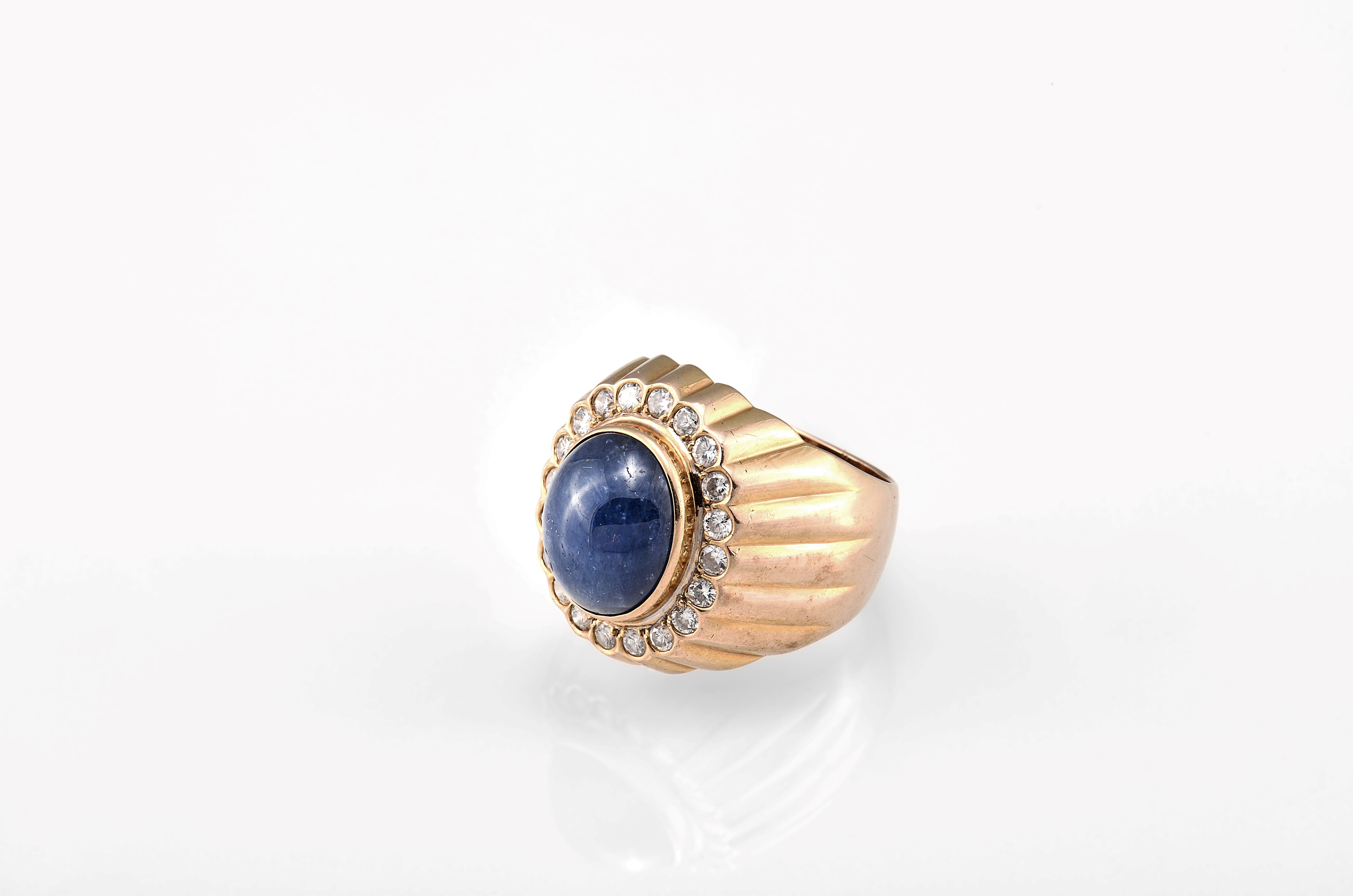 This ring features an oval-shaped natural blue sapphire cabochon at the center, measuring approximately 13.1 x 11.2 x 7.4 mm. The sapphire is beautifully framed by natural diamonds, all set in 14K yellow gold. The ring is approximately size 7.5 and