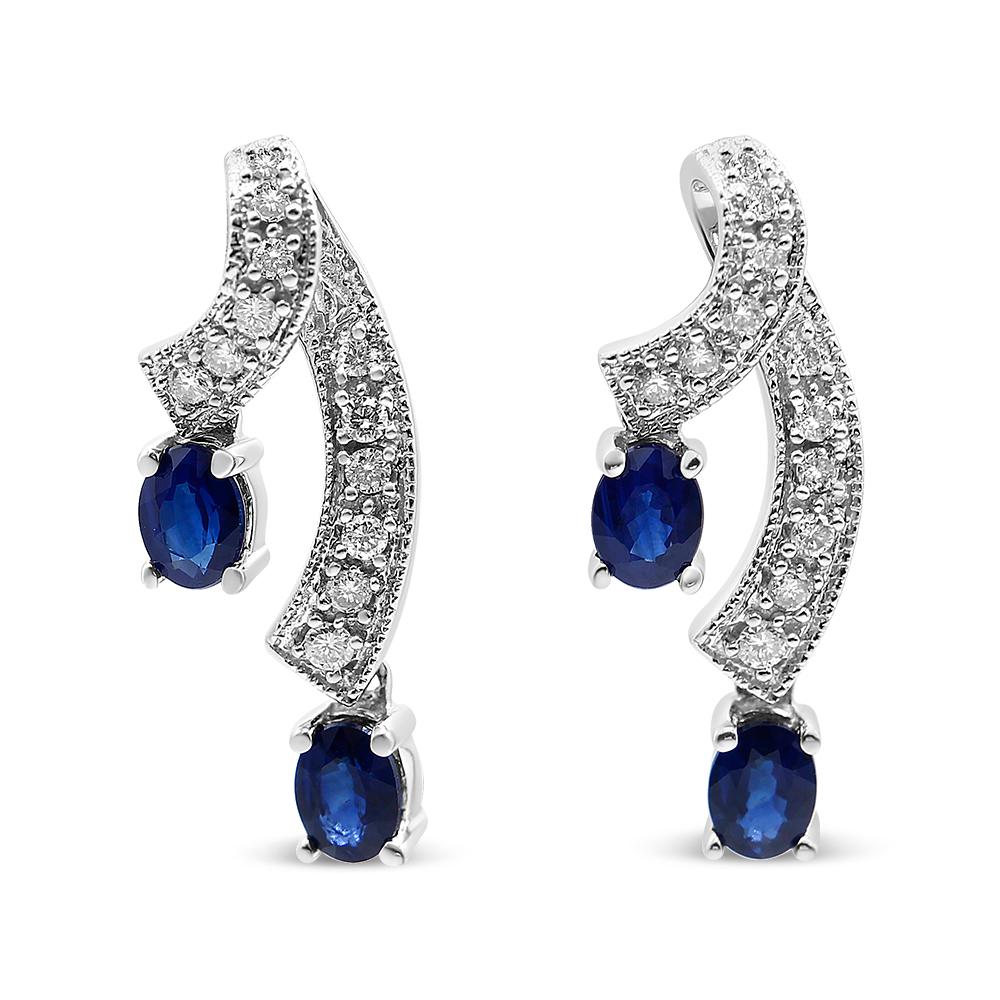 These unique earrings are sure to turn heads. Each earring features two ribbons of diamond accented 14K White Gold weaving through down your ear. The diamond studded ribbons end with 4 beautiful, natural blue sapphires. Radiating a glorious blue