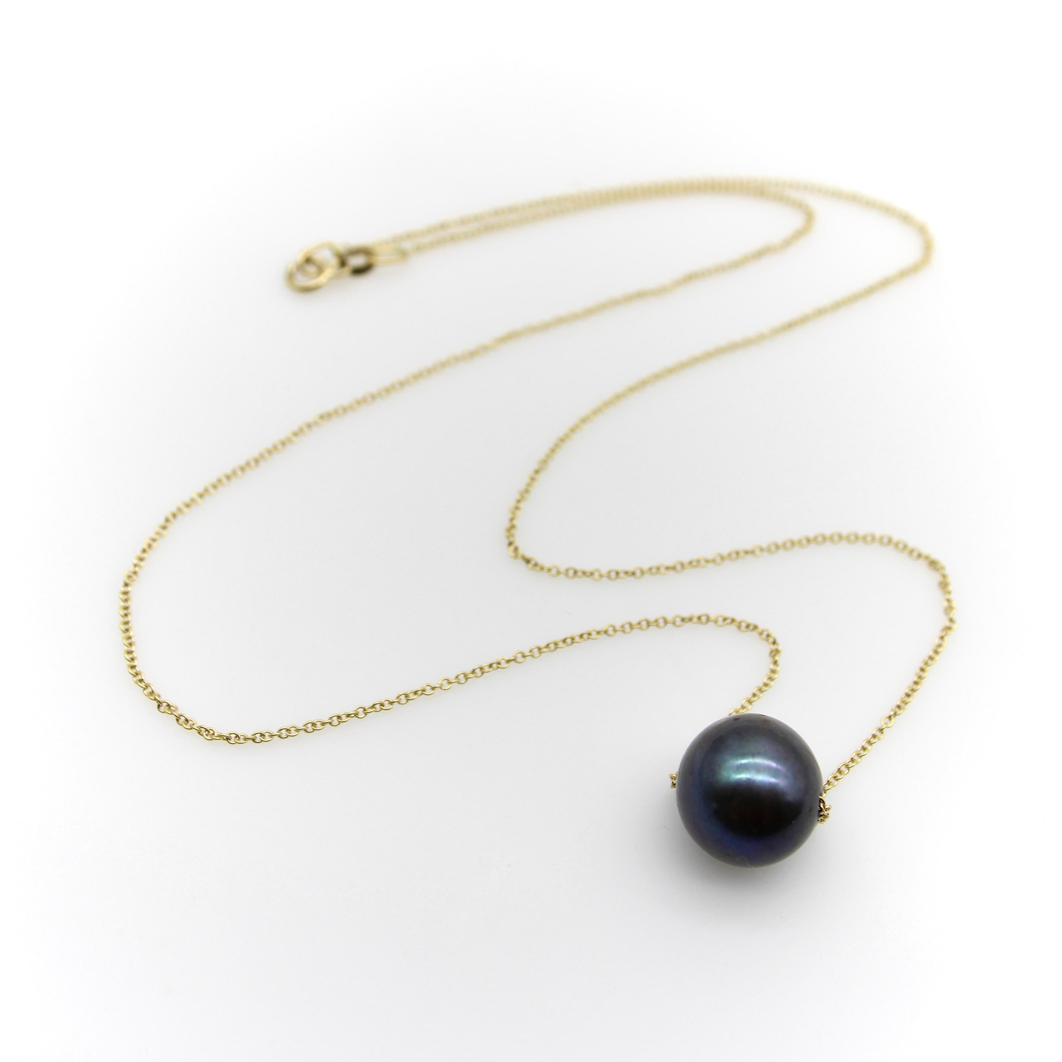 Este collar de oro de 14k tiene un aspecto minimalista y sofisticado con una perla negra de los Mares del Sur como pieza central. La perla negra tiene bellos matices de verde, azul y gris oscuro cálido. Tiene una buena forma redonda y un nácar