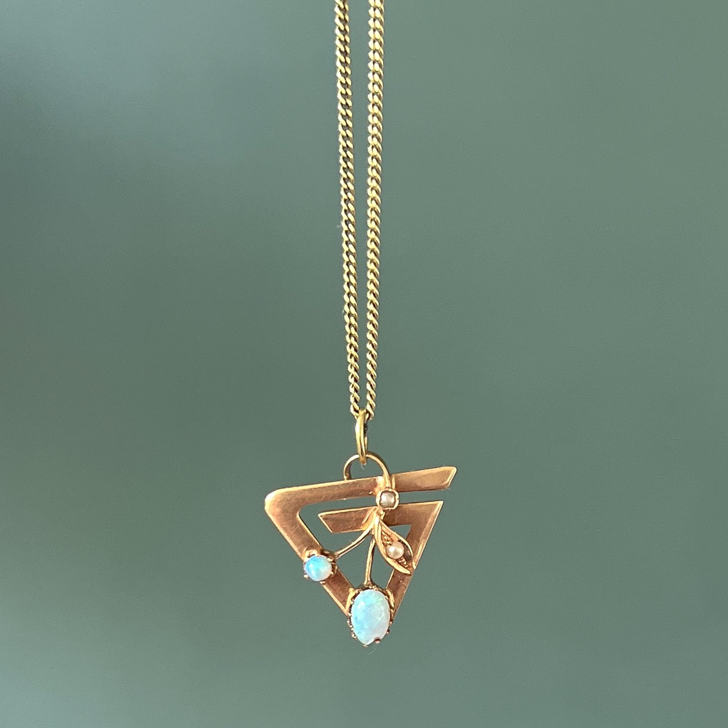 Ein 14 Karat Gold Opal und Saatperle Vintage Charme Anhänger. Dieser gebrauchte Charme hat ein florales Blattdesign, das mit zwei winzigen Saatperlen und zwei schönen weißen Opalen besetzt ist. Der Rahmen wird als Dreieck modelliert.