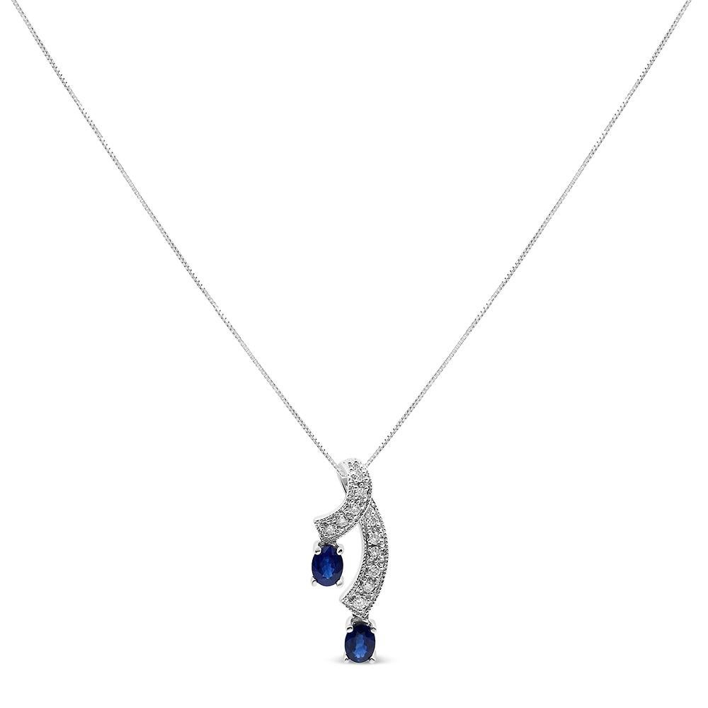 This unique pendant necklace is sure to turn heads. The pendant features a a ribbon of diamond accented 14K White Gold weaving through down neckline. The diamond studded ribbon ends with 2 beautiful, natural blue sapphires. Radiating a glorious blue