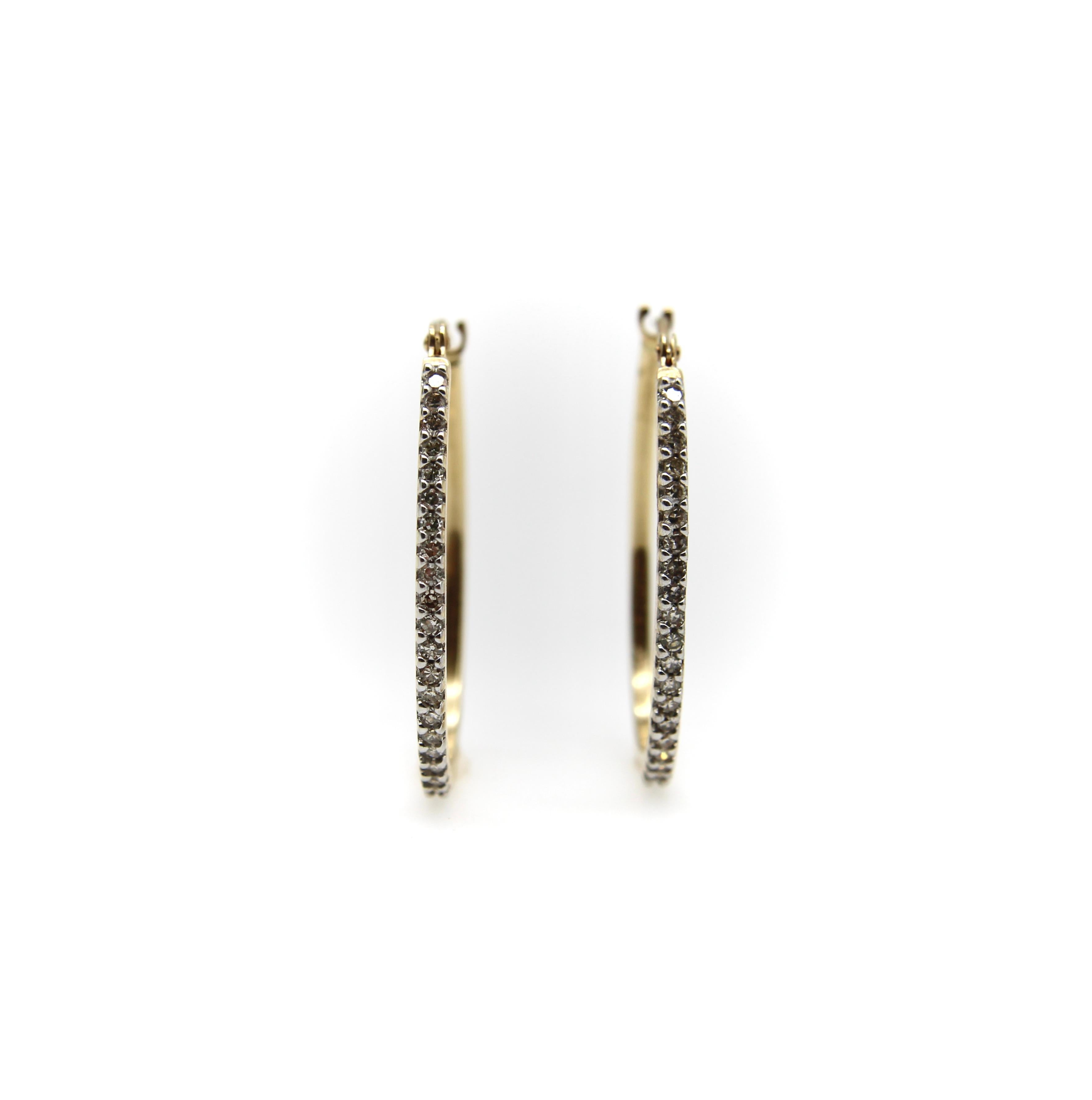 Questi orecchini a cerchio ovali con diamanti in pavé in oro 14k sono l'aggiunta ideale a qualsiasi collezione di gioielli. I cerchi ovali allungati sono in oro giallo, ma le incastonature che tengono fermi i diamanti sono in oro bianco per rendere