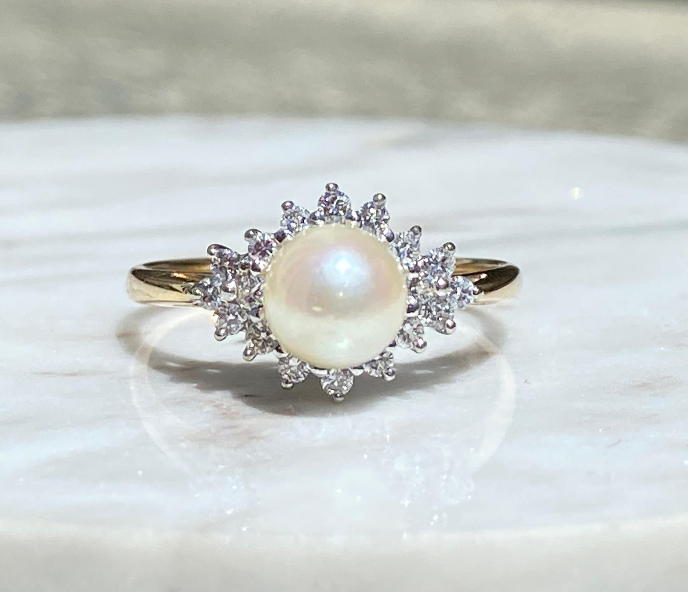 One lady's 14k yellow and white gold ring featuring a 6.4mm round cultured pearl and 0.18tcw of I/J color and SI clarity round brilliant diamonds, stamped 14k. The ring weighs 2.4 grams and is a US size 7. The ring is sizable, but this is not a