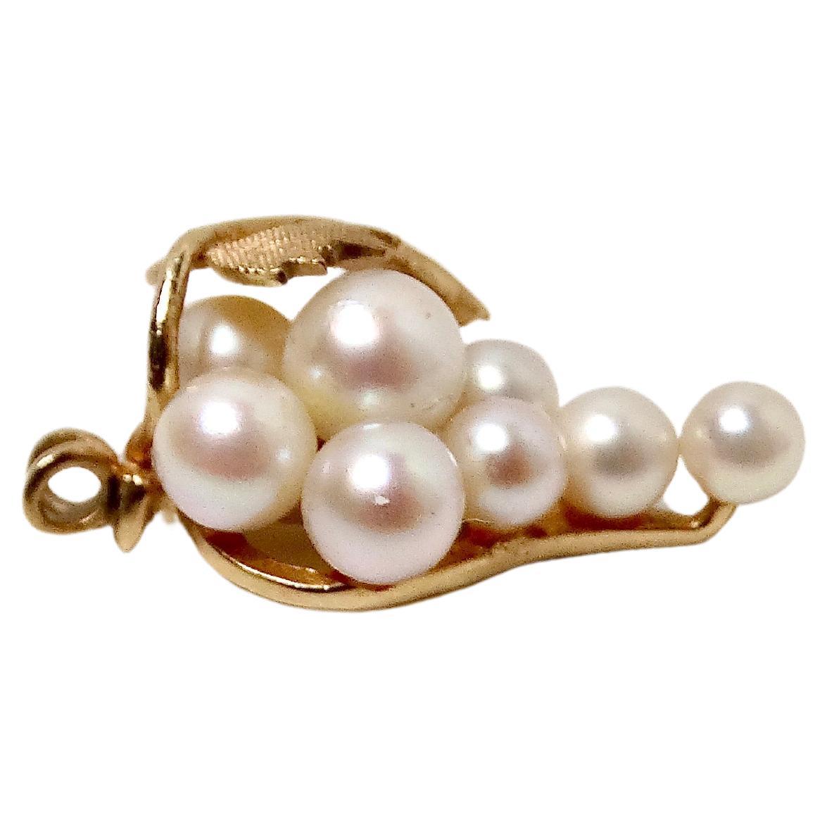 Questo raffinato ciondolo in oro 14k e perle, risalente agli anni '40 circa, è un esempio di eleganza senza tempo e di maestria artigianale. Realizzato in delicato oro a 14 carati, il ciondolo presenta una foglia dal design intricato che culla un