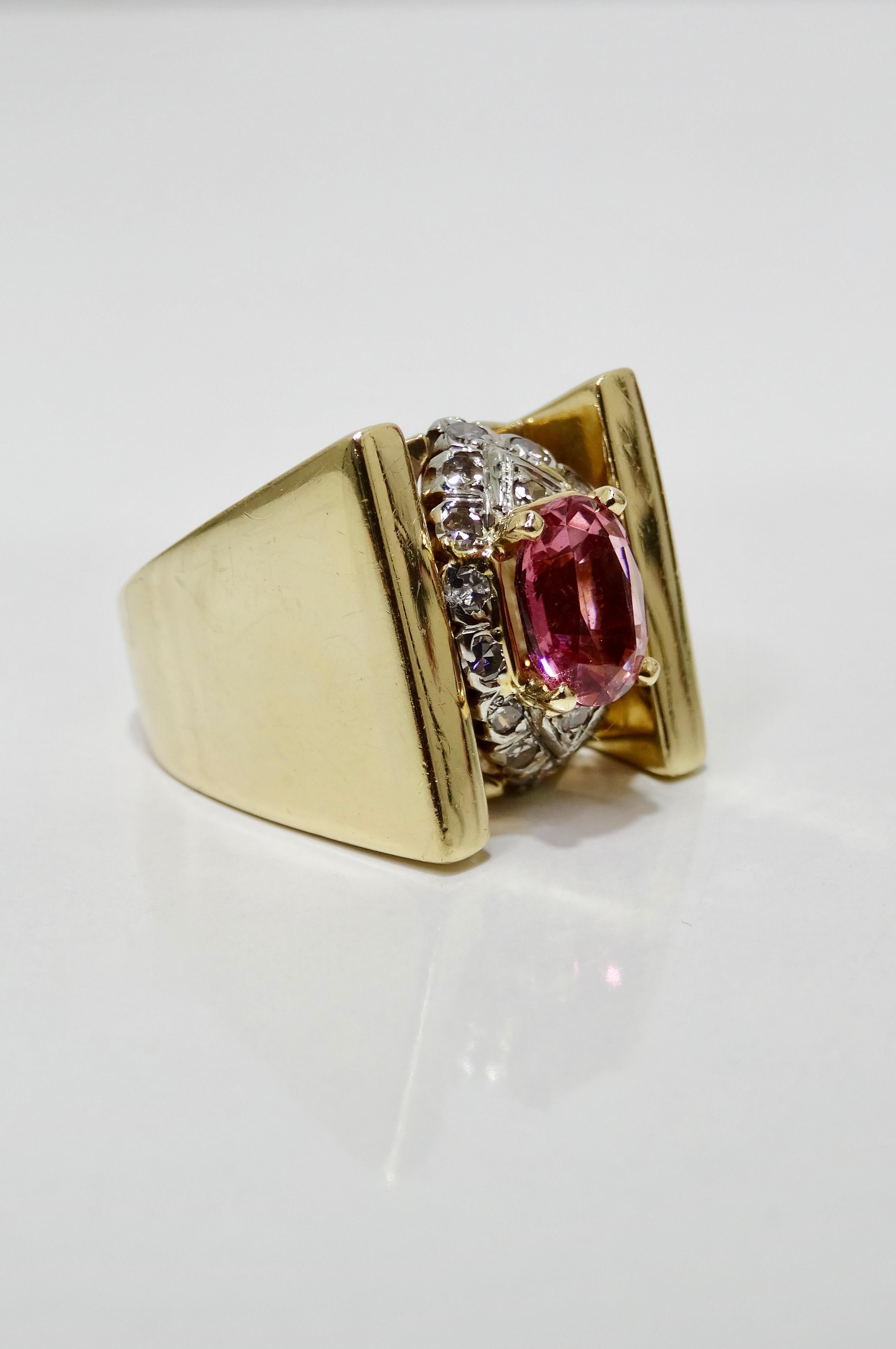 Elegant with a pop of color, this mid-20th century cluster ring is crafted from 14k Gold and features a thick tension band. Resting in the center prong setting is a stunning pink oval Tourmaline framed by a cluster of brilliant round cut diamonds.