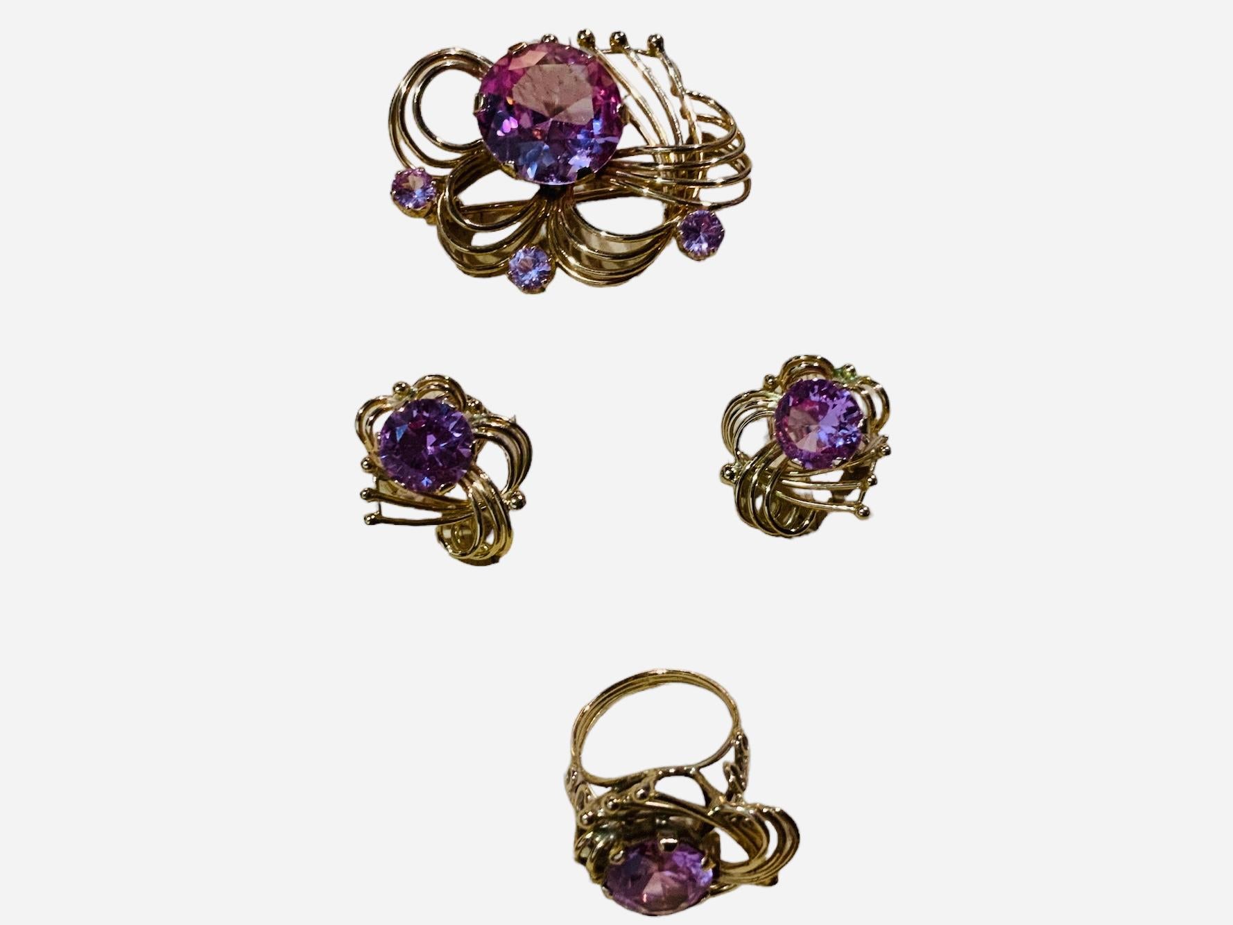 This is a 14K Gold Pink Sapphires Parure. It depicts a yellow gold brooch, pair of earrings and ring that contain seven brilliant shape created Pink Sapphires weighing 40.71 carats. Mount made in 14k yellow gold. Its weight is 34.8 grams. The ring