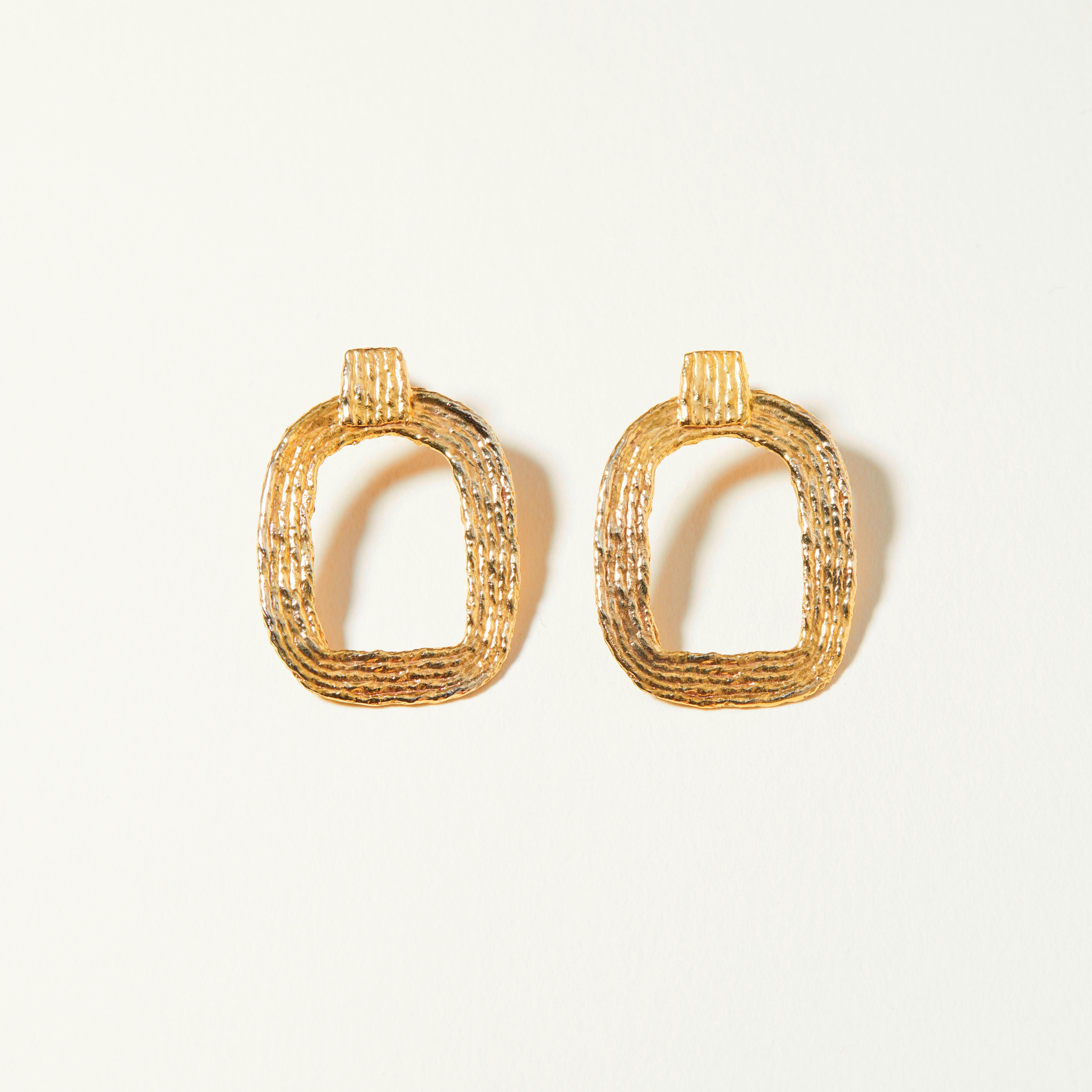 Inspired by artist Eva Hesse, the Eva Earrings are a pair of contemporary statement earrings made from 14K gold plated, reclaimed brass. These statement earrings consist of two, rounded rectangles cleverly balanced with a square detail, providing a