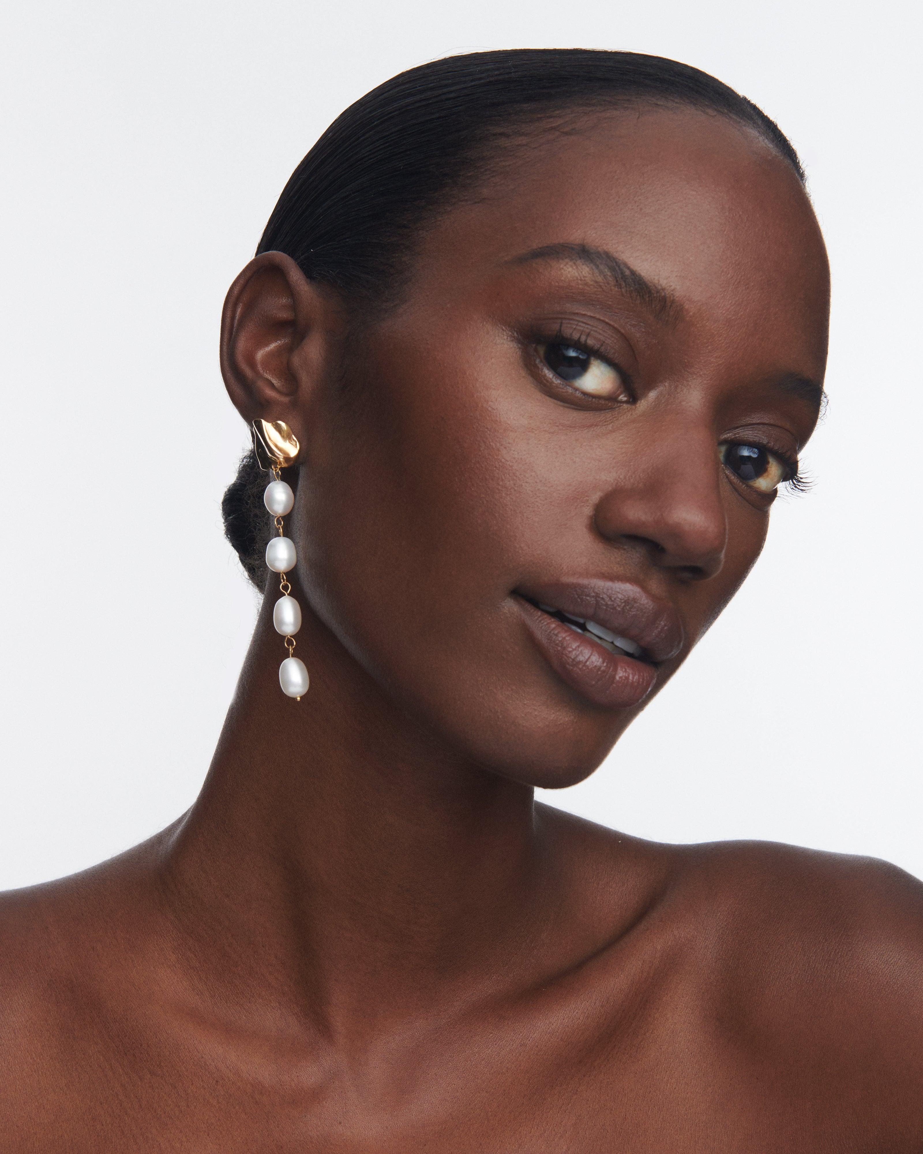 The Lucite Drip Minis are lightweight, dangling earrings that feature Molten 14k gold plated studs with four dangling freshwater pearls. Wear them during the day with hair down and a casual top; transition to the evening by tying your hair up to