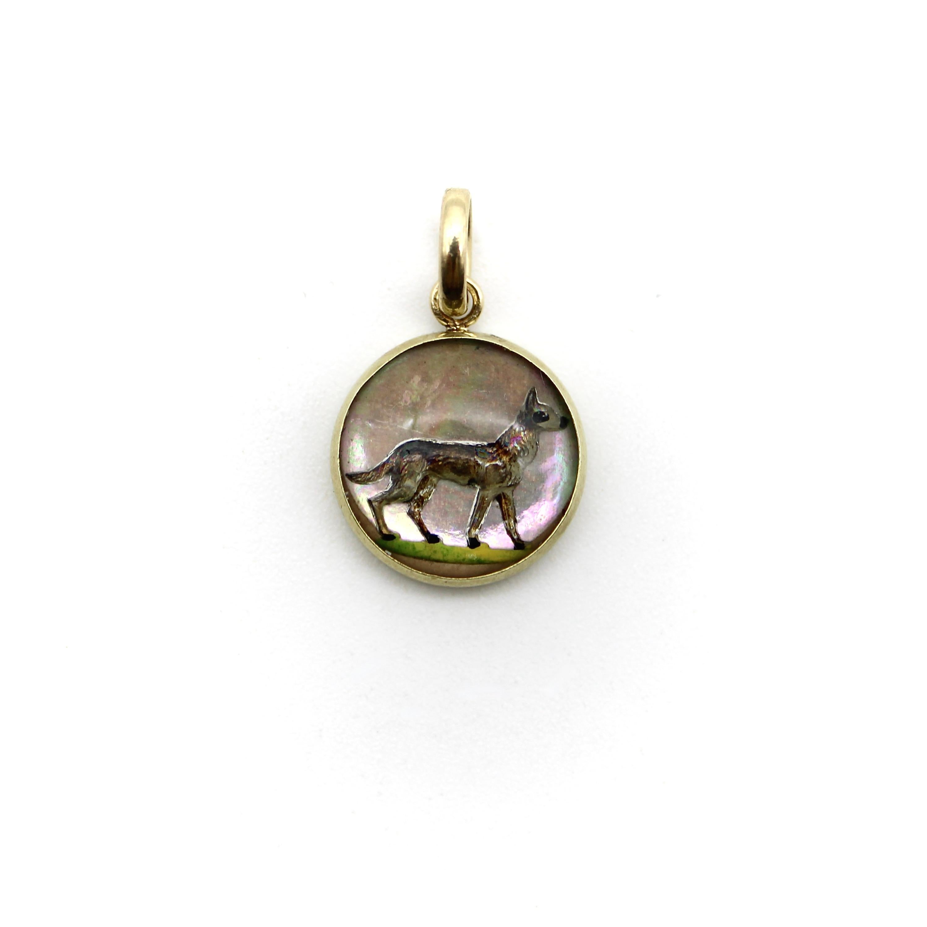 This circular pendant is cast from glass, with a dog carved and hand painted to shine through in a lively, three-dimensional effect. The dog is similar to a German Shepard, and it stands on a patch of green grass that adds cheerful color to the