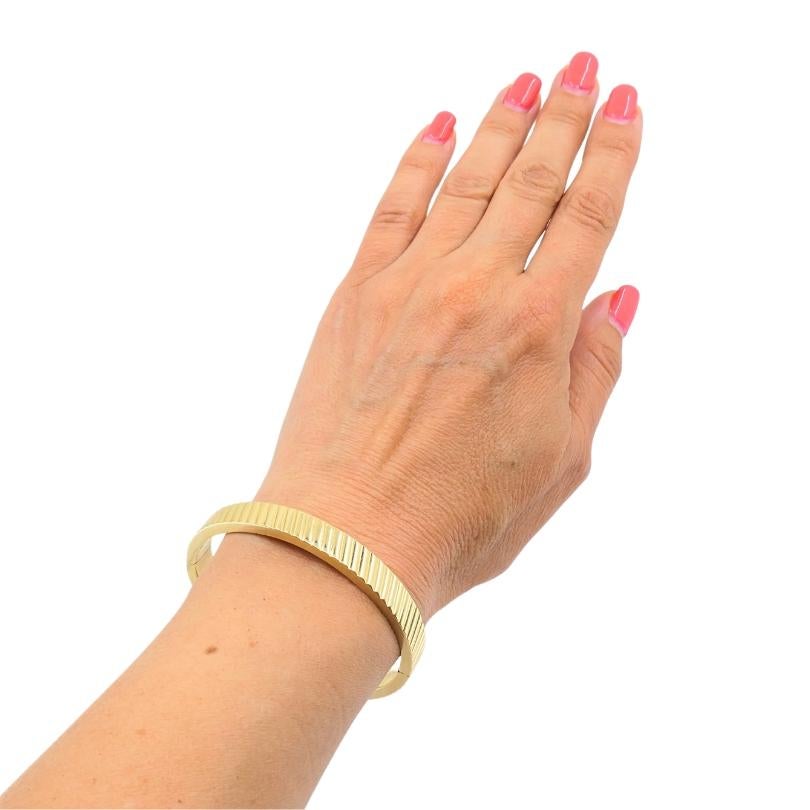 Bracciale bangle in oro 14k vintage dal design minimal.u2028La superficie del bracciale è avvolta da nette nervature diagonali. Questo motivo strutturato si sviluppa in un'unica direzione lungo tutto il perimetro, creando un ritmo e un movimento