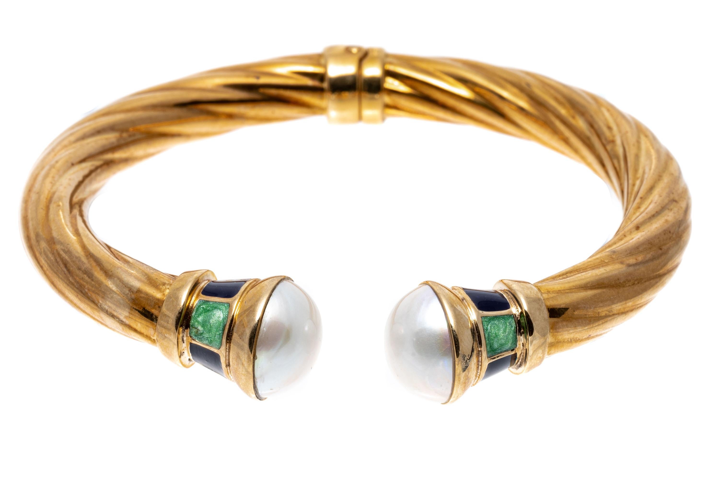 14k Yellow Gold Ribbed Open Cuff Bangle Bracelet Set With Mabe Pearls And Green And Blue Enamel.
This colorful bracelet is a hinged, open ribbed cuff style bangle, with cultured mabe pearl ends, decorated with collars of alternating pale green and