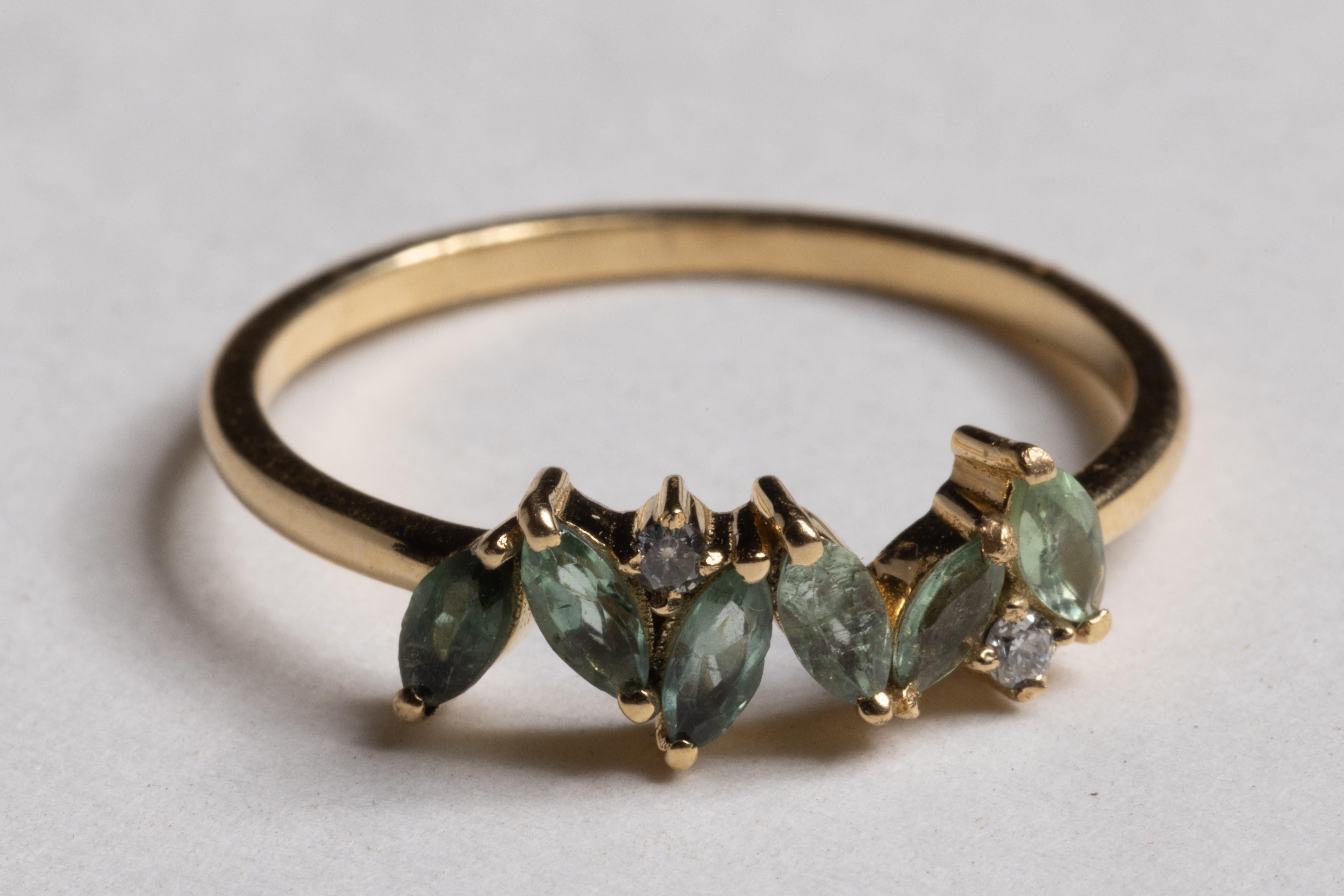 Un grazioso grappolo di sei gemme di tormalina verde sfaccettate a forma di marquise con due diamanti rotondi a taglio brillante intervallati.  Le tormaline verdi ammontano a 0,38 carati.  La misura dell'anello è 6,5

La collezione di alta