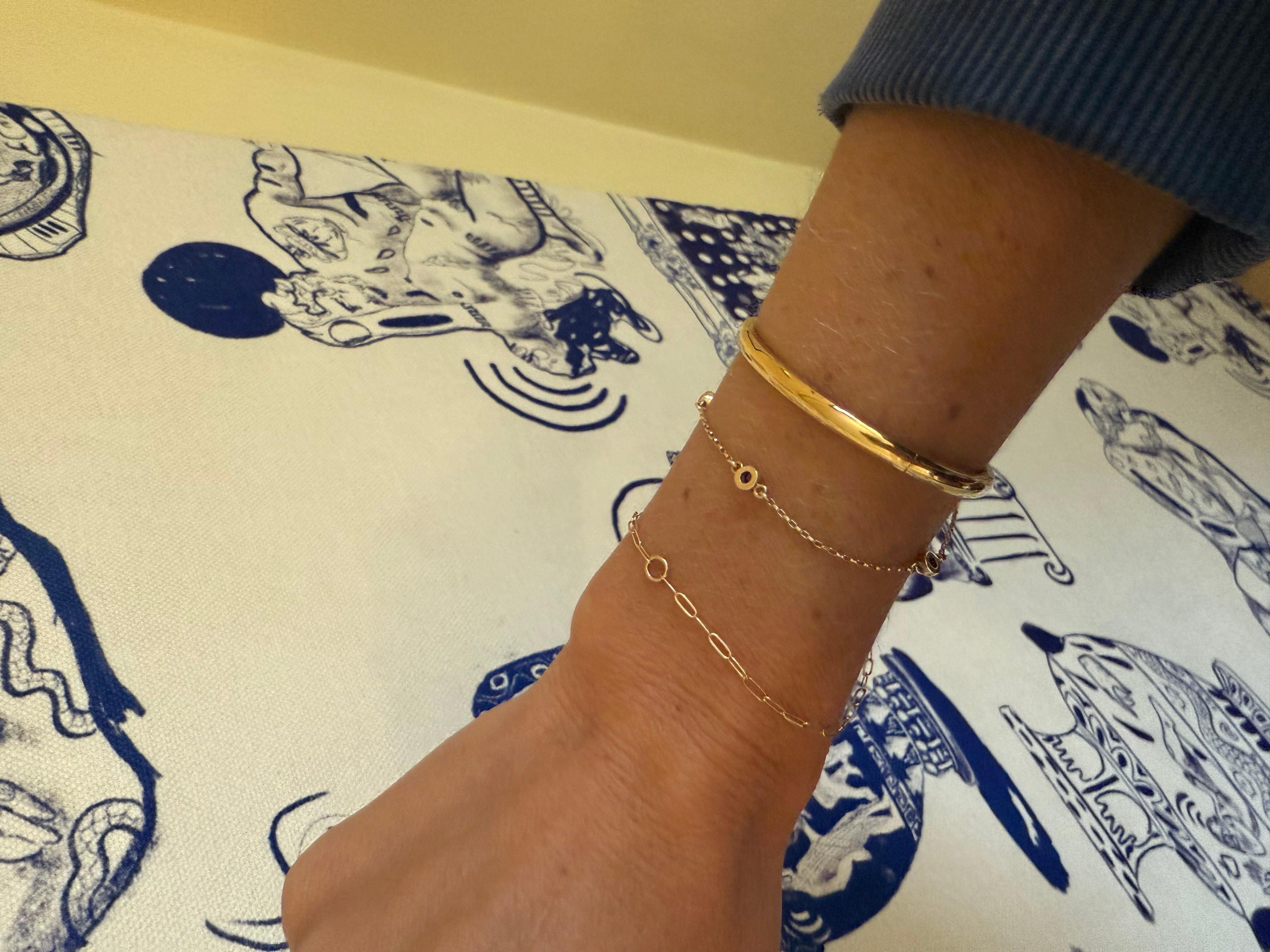 This 14k gold round bangle is a timeless piece that will add a touch of elegance to any outfit. The simple, chic design features a round band with a buckle clasp that is both comfortable and easy to put on and take off.