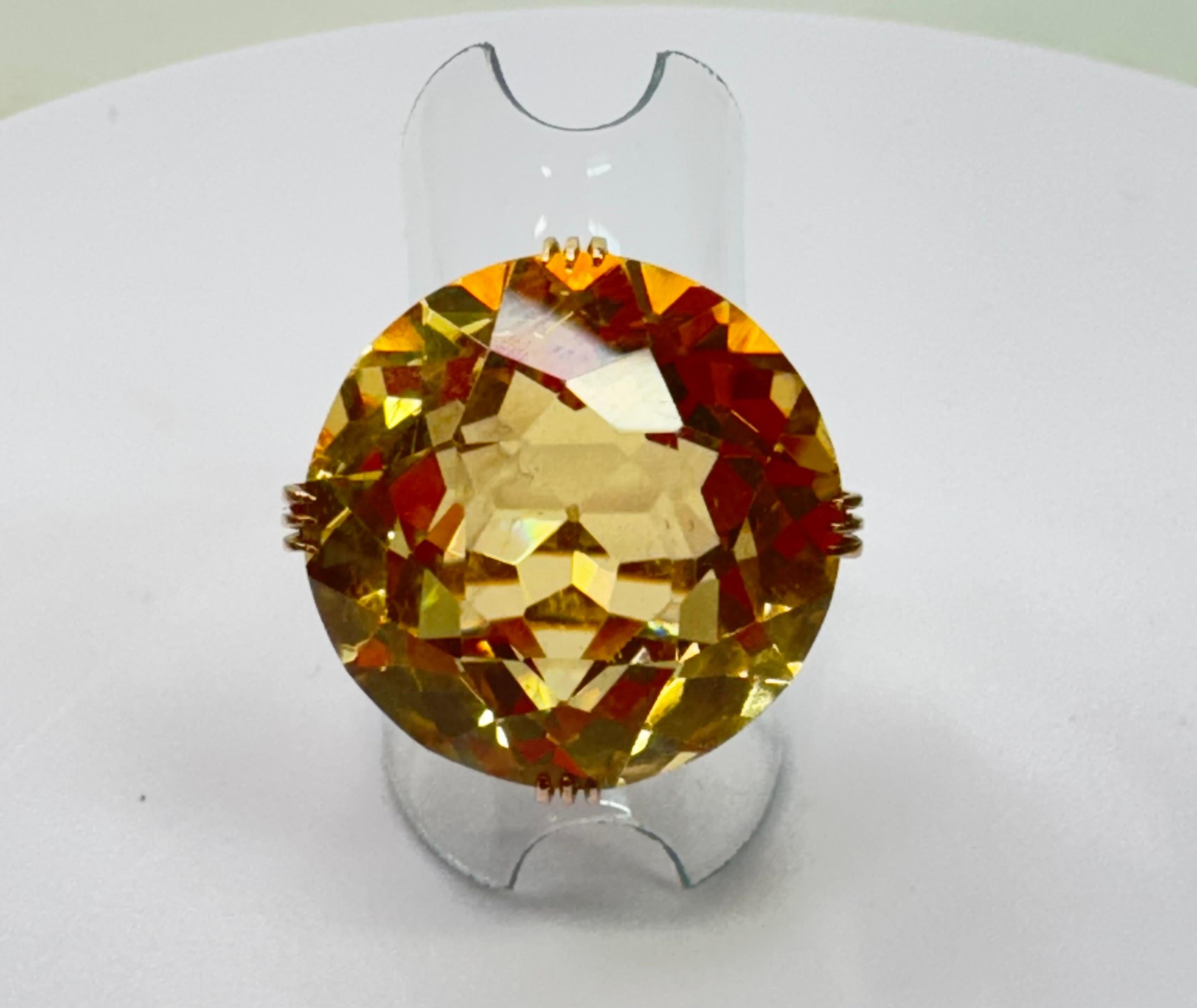 Cette pièce présente une superbe citrine ronde sertie dans de l'or 14k. La citrine est facettée pour en rehausser l'éclat et présente une riche teinte dorée moyenne. Mesurant environ 21,5 mm de diamètre, y compris les griffes, cette pierre précieuse