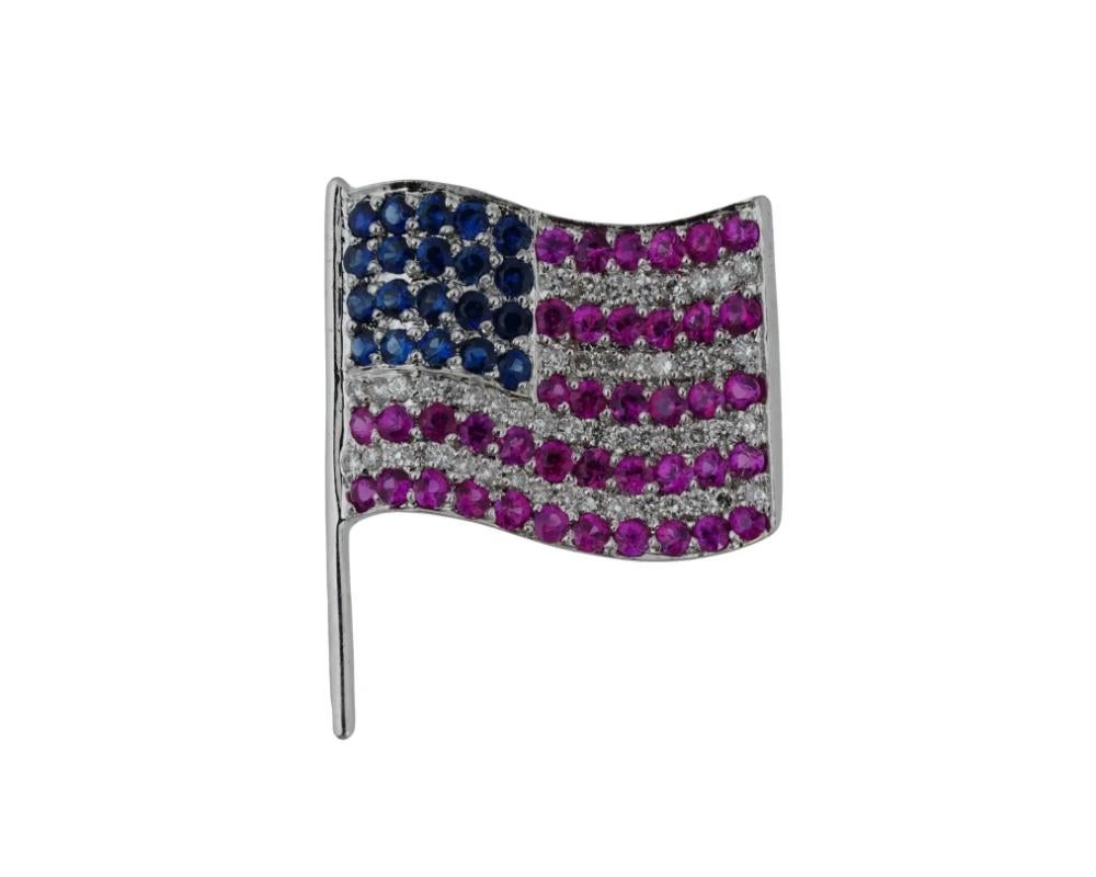 A vintage 14K white gold pin brooch representing the American flag. The piece is garnished with round-cut rubies, sapphires, and diamonds. Marked 14K, 585 on the backside. Total Weight: 3.2 grams. Mineral Stone Jewelry And Lapel Accessories,