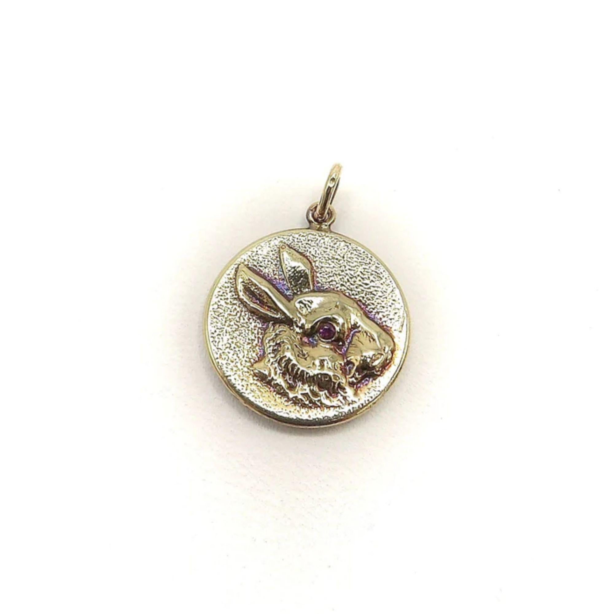 This is a precious 14k gold medallion charm from Kirsten’s Corner signature “Cute as a Button” collection. It is handcrafted and molded from a Victorian-era button and features a portrait of a rabbit. The face has striking ruby eyes that offer a