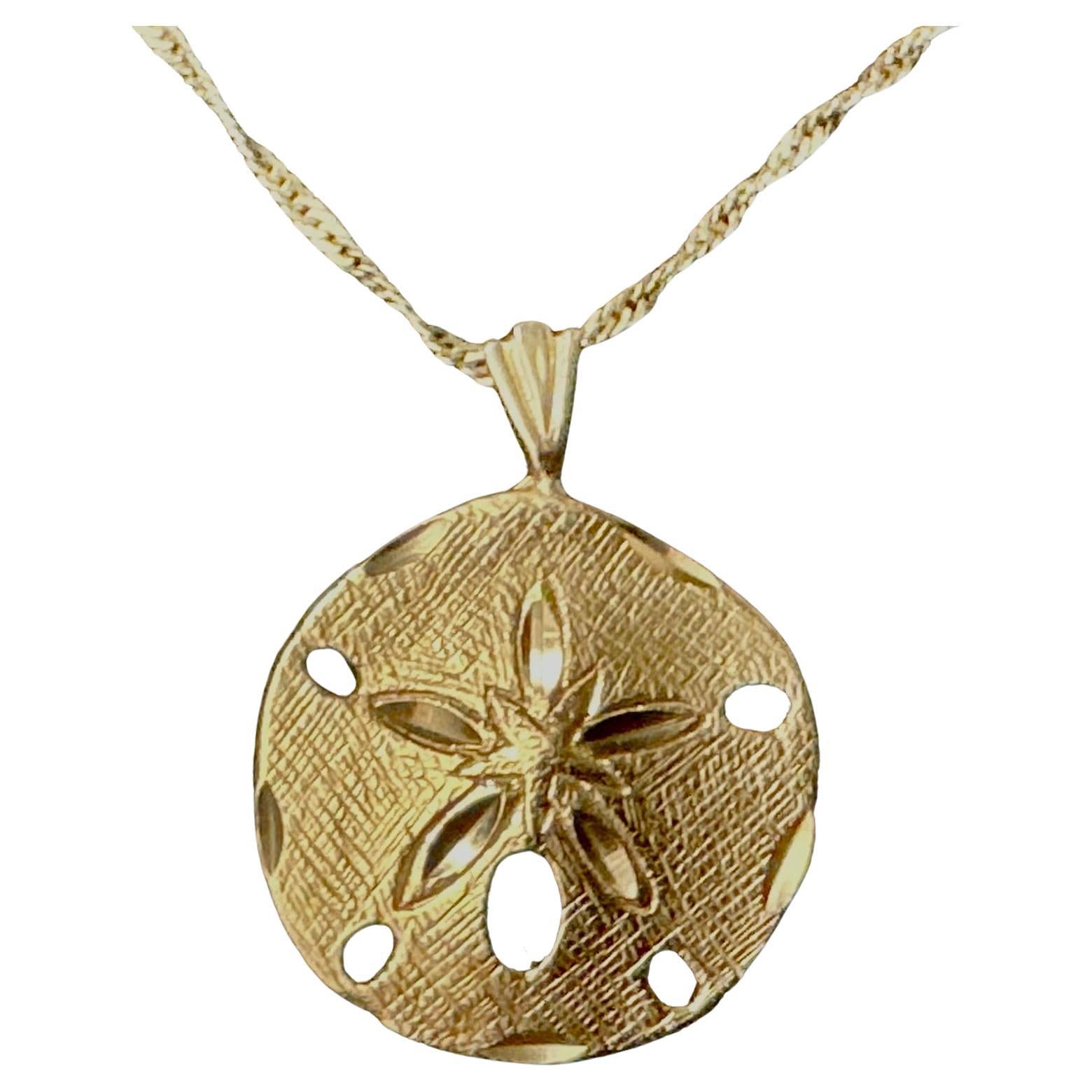 14K Gold Sand Dollar Pendant. Pendant features finely detailed textured surface and cutout accents that capture the natural beauty of the seashell form. Pendant measures 0.75
