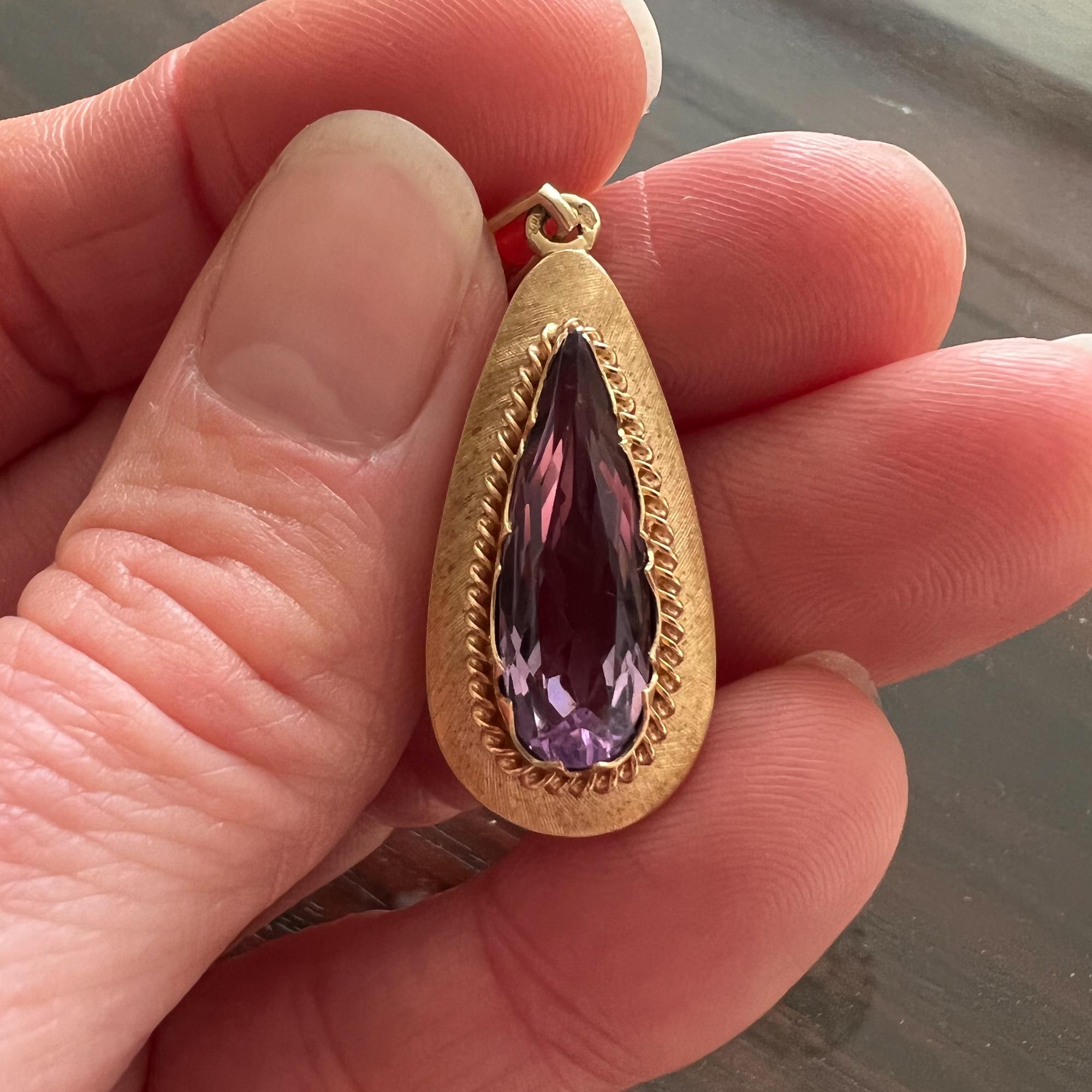 An amethyst drop-shaped vintage pendant crafted in 14 karat gold. The pendant is set with a translucent faceted amethyst stone. The amethyst is light purple in color, the stone is faceted and bezel set in a gold worked matted frame which has a