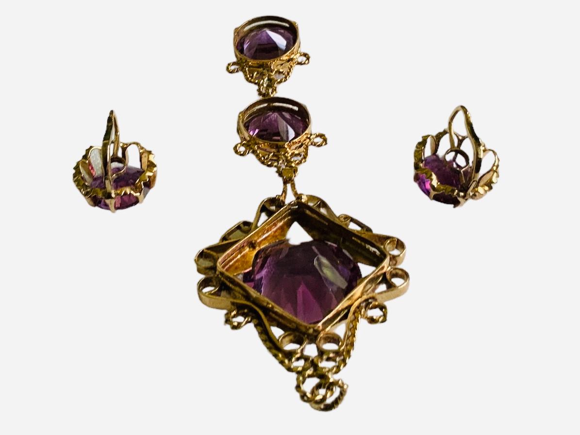 This is a 14K Gold Set of Amethyst Pendant and Pair of Earrings. It depicts a yellow gold amethyst drop pendant made of three graduating round faceted amethysts stones in prong setting. The bigger stone is at the top and adorned with a diamond