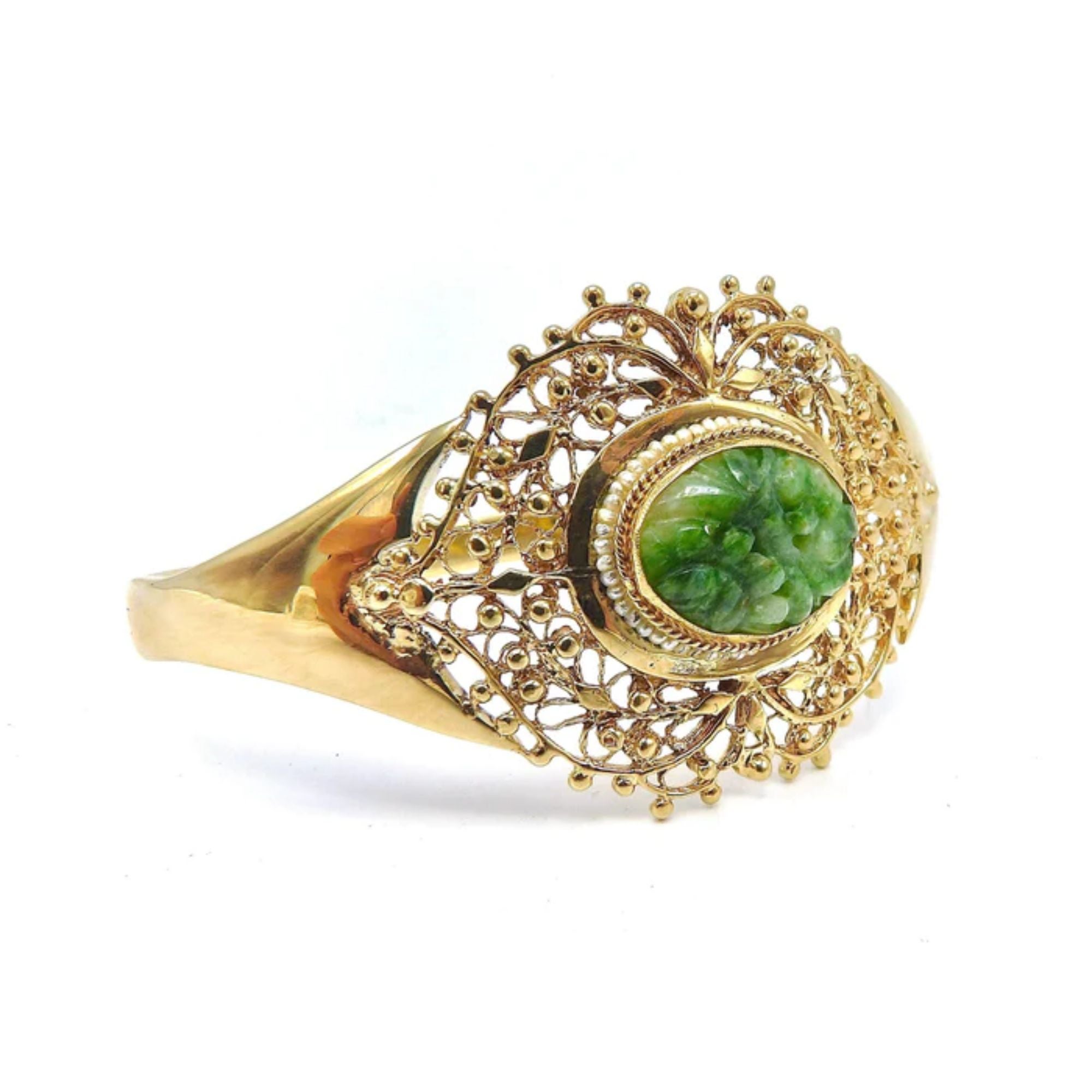 This elegant bracelet is made of 14k gold and decorated with a central reticulated piece of green jade. The center jade piece protrudes about a 1/4 of an inch from the gold setting and is carved with flower patterns. A lovely ring of seed pearls