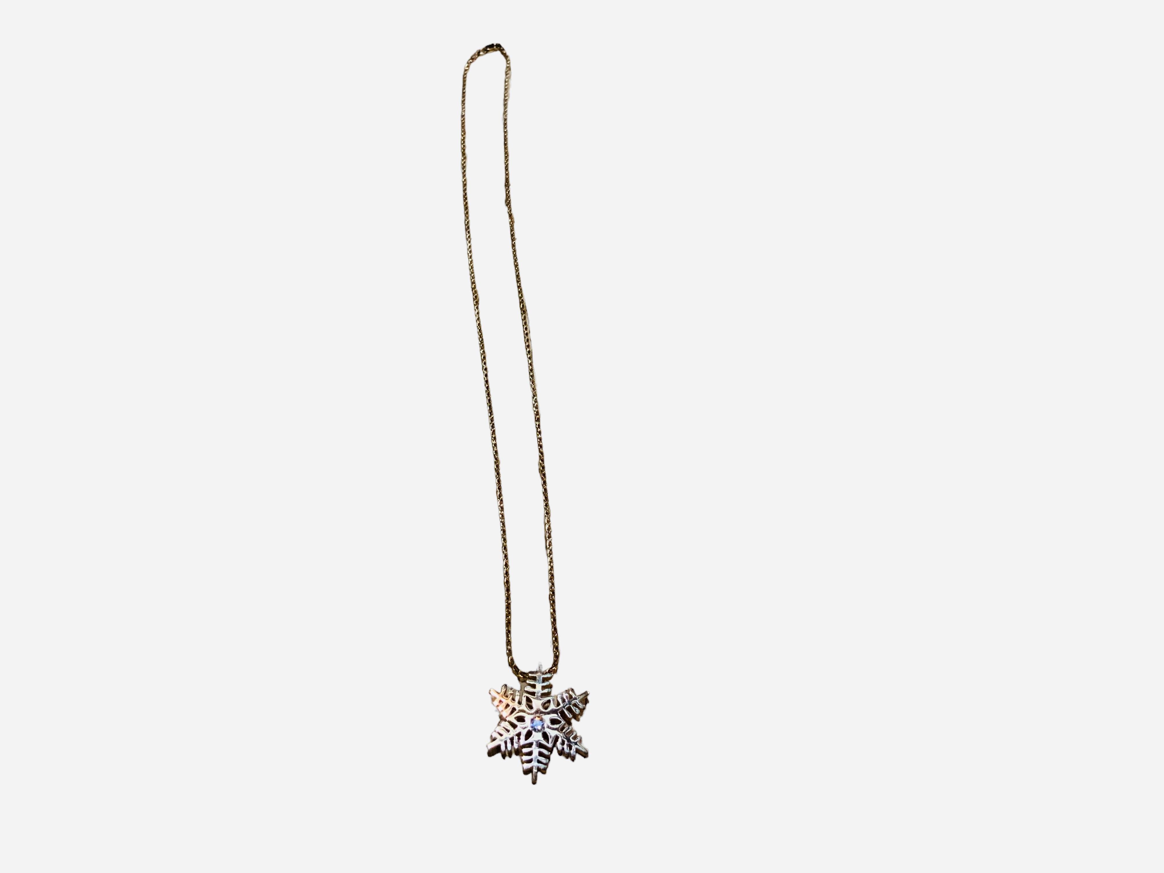 This is a 14K gold snowflake pendant necklace. It depicts an hexagonal shaped snowflake ( weight- 4.5 grams ) with a round diamond (0.08ct, E-F color and VVS- VSclarity) in a bezel setting in the center.  The necklace is a gold rope chain of 20