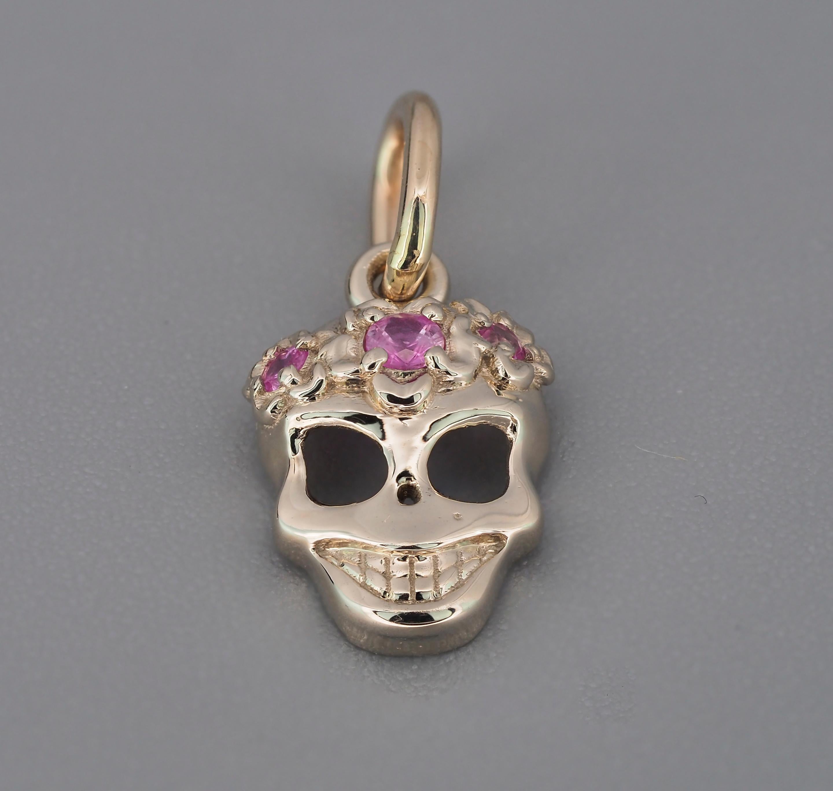 Pendentif Scull en or 14 carats. Pendentif Hallowen.  Pendentif en forme de scarabée. Pendentif Memento Mori en or.  Collier en forme de crâne souriant.

Poids : 1,2 g.
Taille : 16,3 x 8 mm.
Serti de saphirs : 3 pièces, couleur rose,