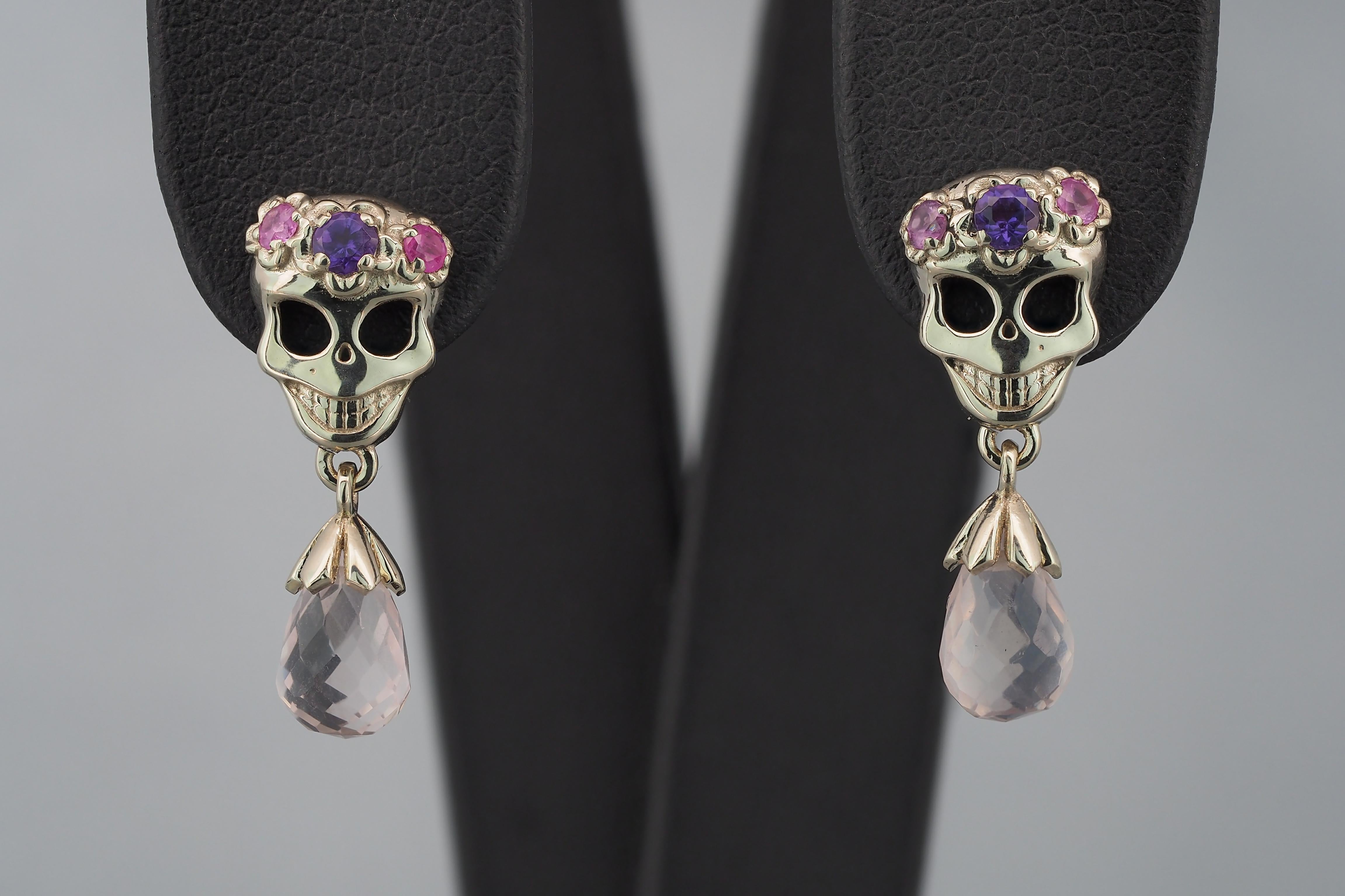 14 kt solid gold skull with flowers earrings studs with amethysts, sapphires and pink quartz. Halloween party jewelry.
Weight: 2.9 g.
Earrings size: 20 x 8 mm.

Gemstones:
Natural amethysts: 2 pieces, weight - approx 0.20 ct total
Violet color,