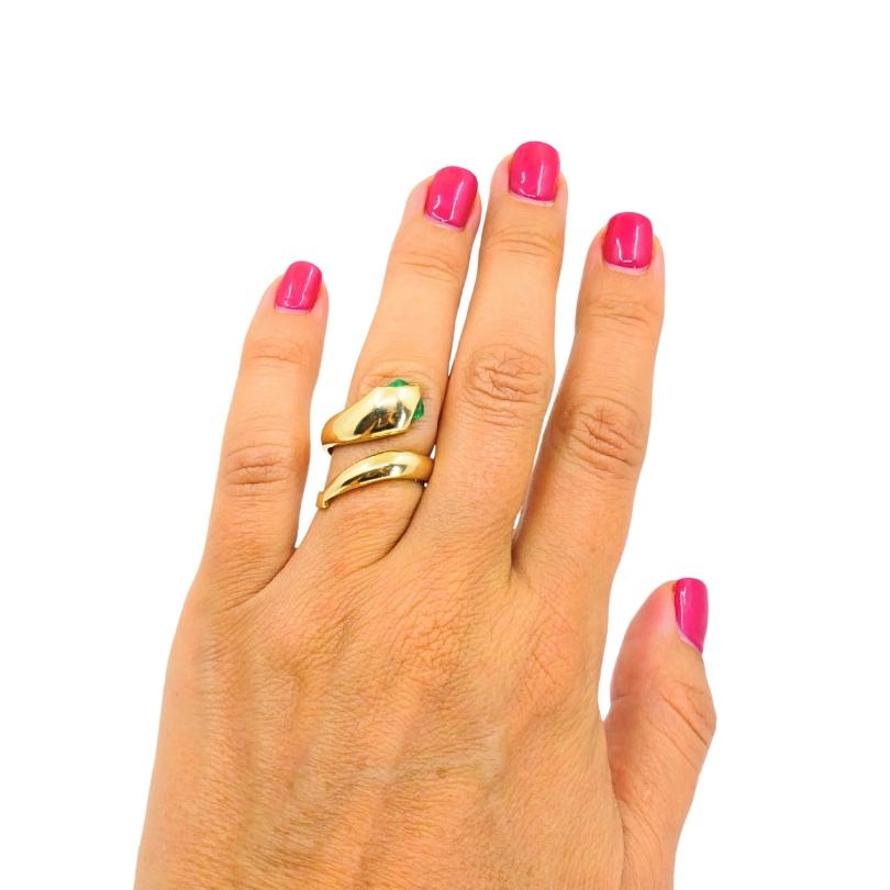 Cette bague vintage remarquable est fabriquée en or jaune 14k et con�çue dans un motif de serpent enroulé, s'enroulant gracieusement autour du doigt. La tête du serpent est ornée de pierres précieuses émeraude en forme de poire pour les yeux,