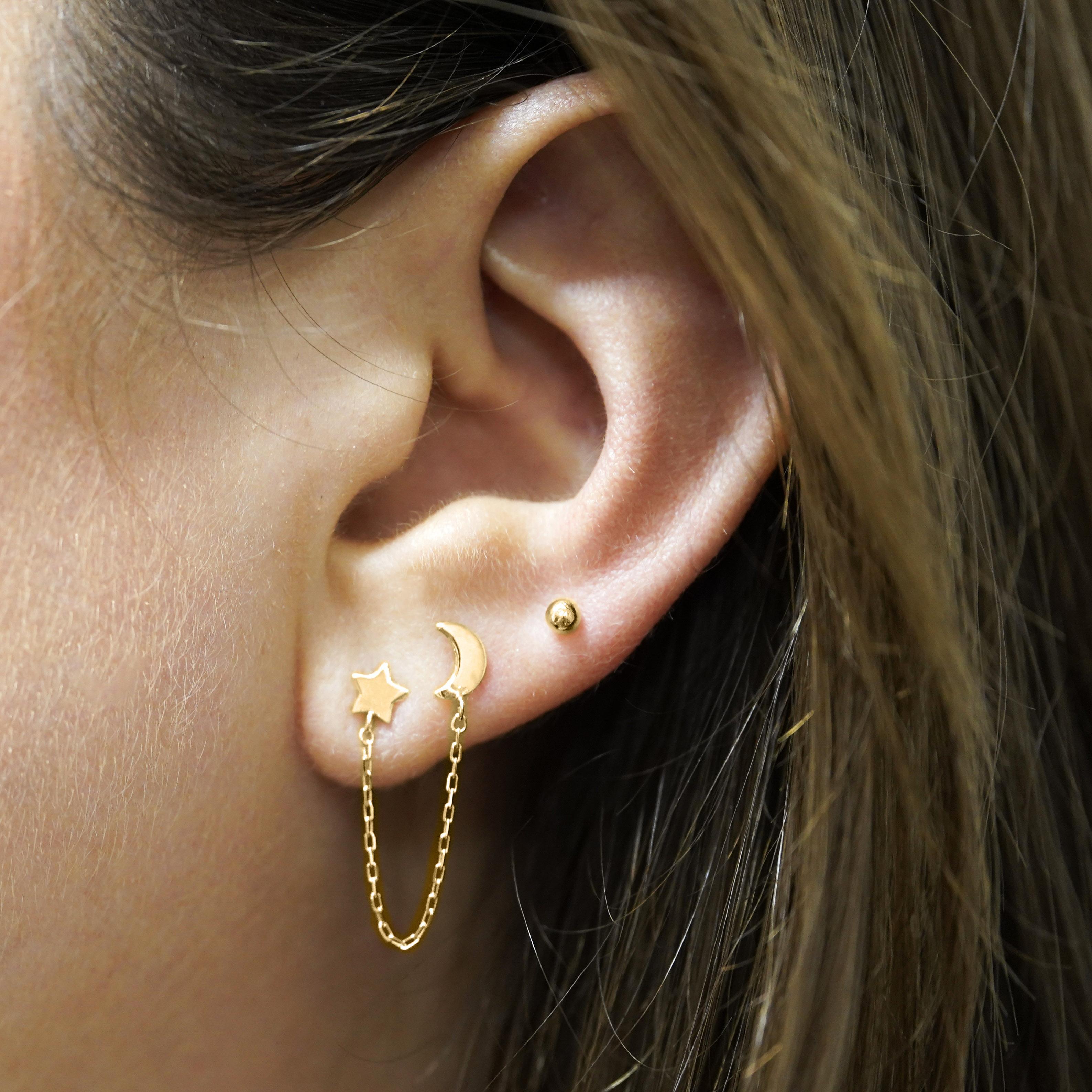 14K gold star and moon celestial double stud earrings, connected by a cable chain for an ethereal, modern look. 

All parts made of 14k solid yellow gold. Not plated or hollow. Sold as a single.

Details:
Item Type: Double Stud Earrings with