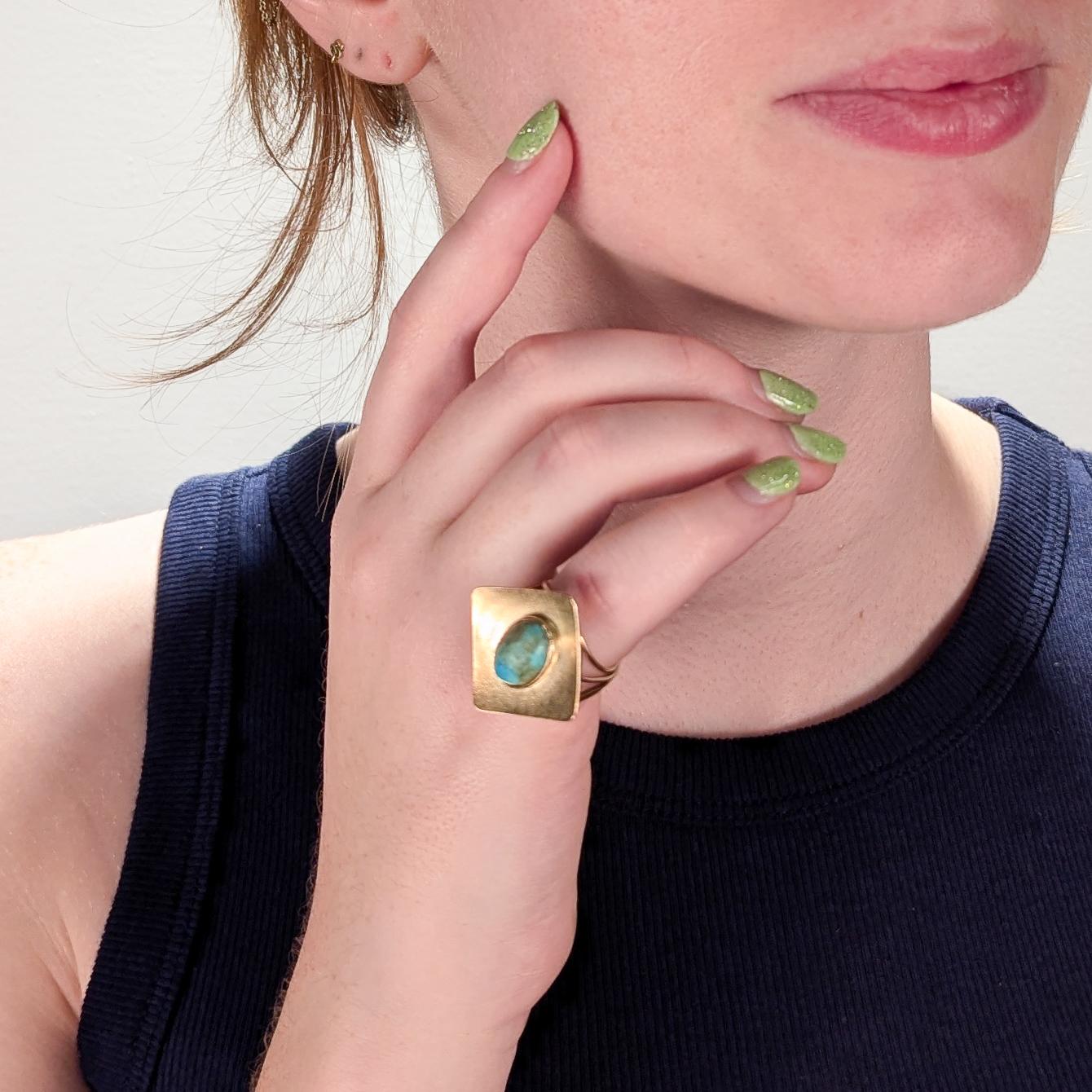 A fine Mid-Century studio cocktail ring.

In 14k yellow gold.

With a bezel set, hand cut turquoise cabochon center set on a wide satellite dish head with a stippled finish. 

Supported on a split wire shank. 

Simply a wonderful piece of handmade