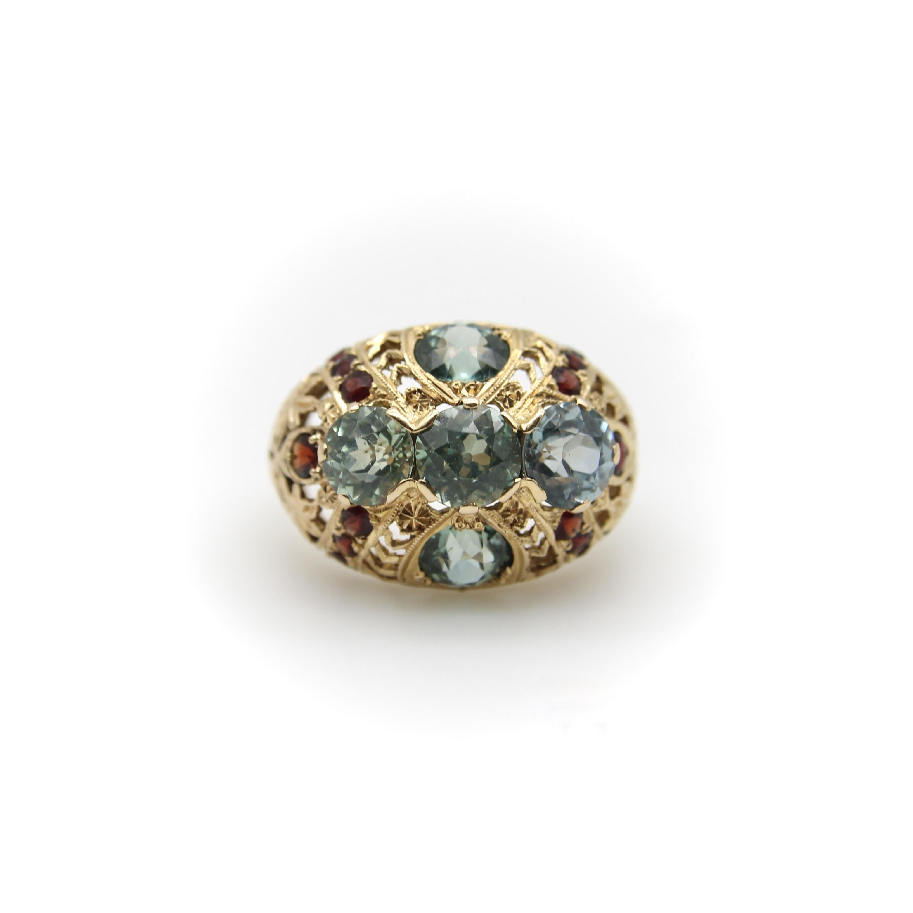 Si tratta di uno splendido anello bombe tardo-vittoriano in oro giallo 14 carati che presenta un motivo floreale simile a un giardino nella lavorazione in filigrana, con delicati fiori e foglie che salgono dalla fascia fino alla cupola della faccia