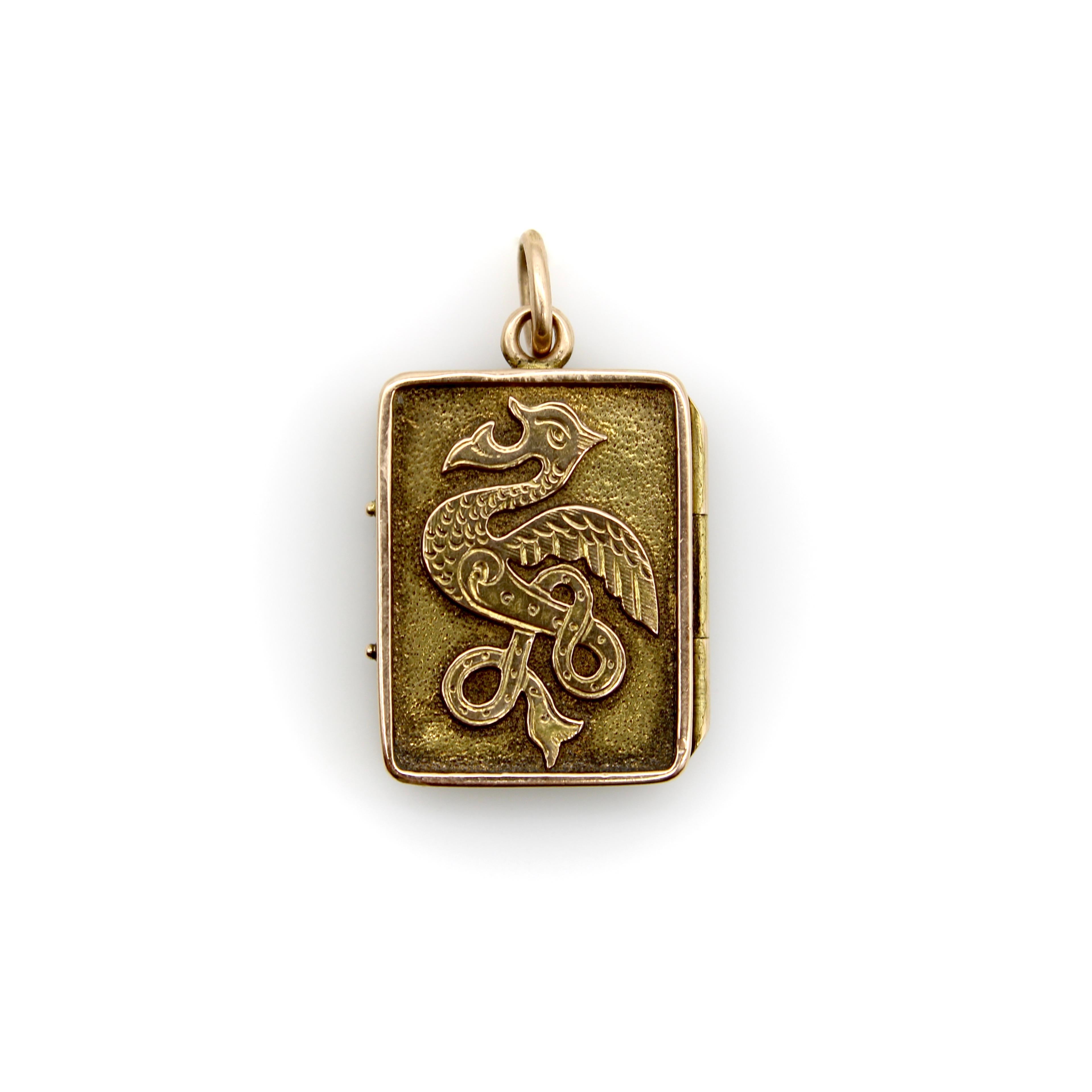 Questo insolito medaglione in oro 14k ha un formato rettangolare e presenta due animali celtici incisi. Da un lato c'è un serpente il cui corpo si attorciglia e si ripiega su se stesso a forma di diamante; dall'altro lato c'è una creatura con le ali