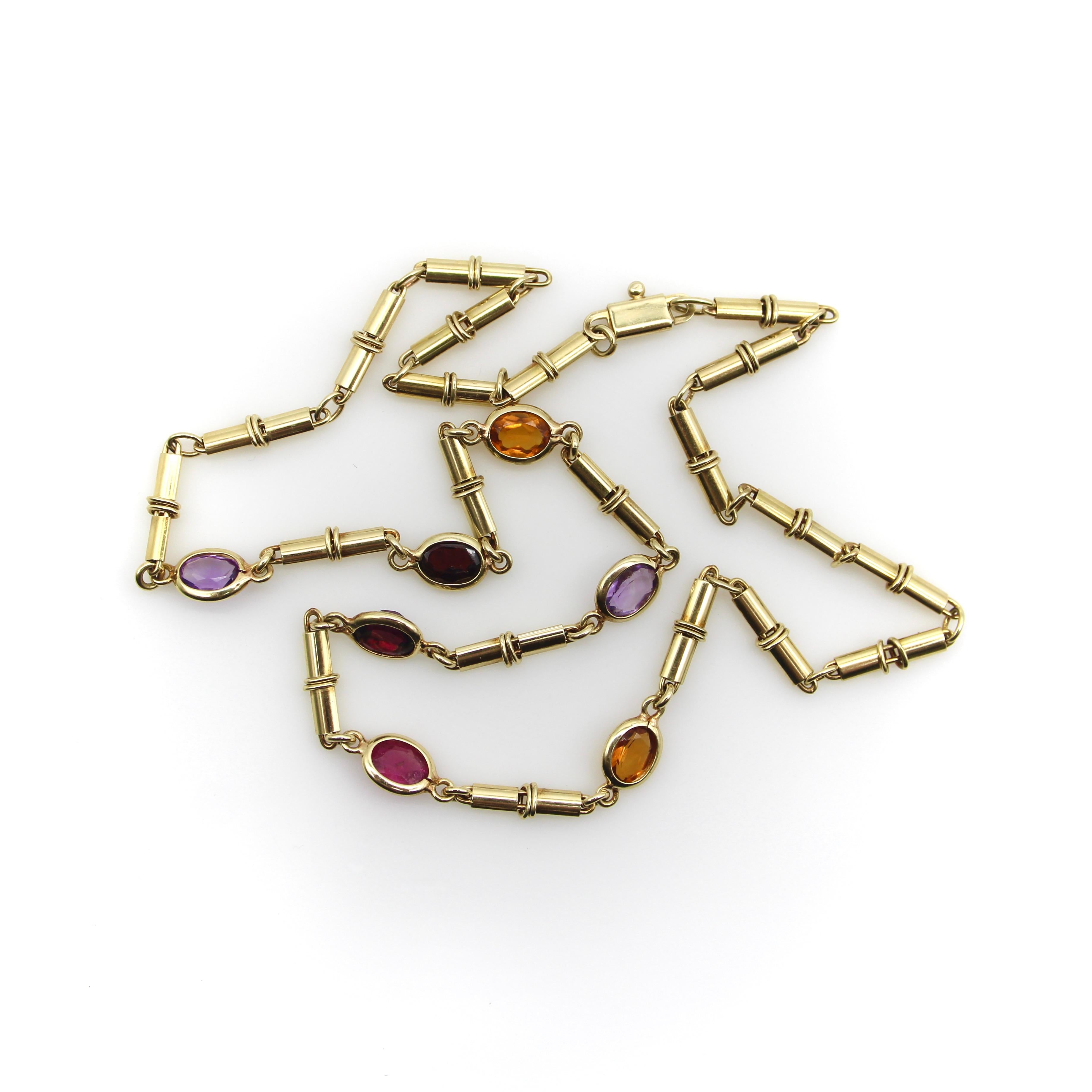 This 14k gold vintage Italian necklace features seven bezel set stones of various colors, providing a rainbow of gems. The stones are connected by elongated tubelike links, creating an intricate texture that looks fantastic layered with other