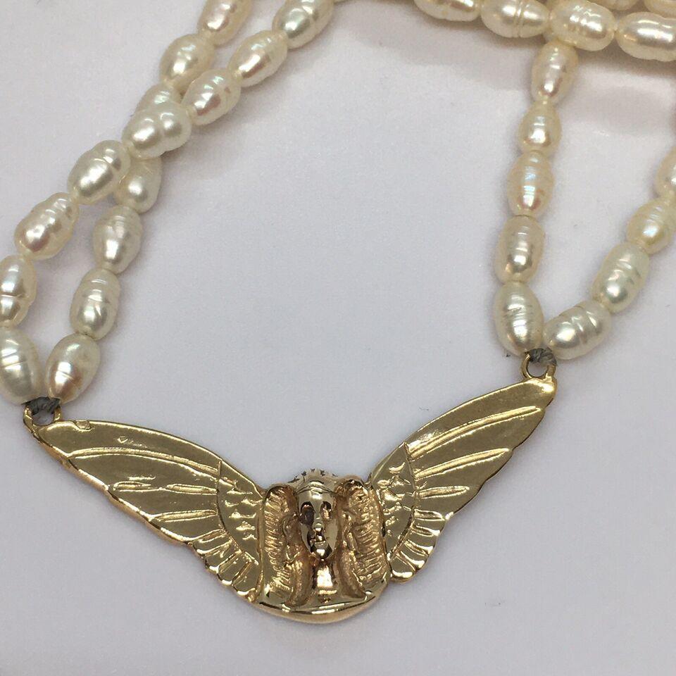 Ciondolo a forma di ali di faraone egiziano in oro 14K Ciondolo con perla di riso 14K

Peso 29.1 grammi
Condit In buone condizioni, nessun segno di riparazioni, vedi foto 
Misure 1,75 pollici di apertura alare, 19 pollici in totale 