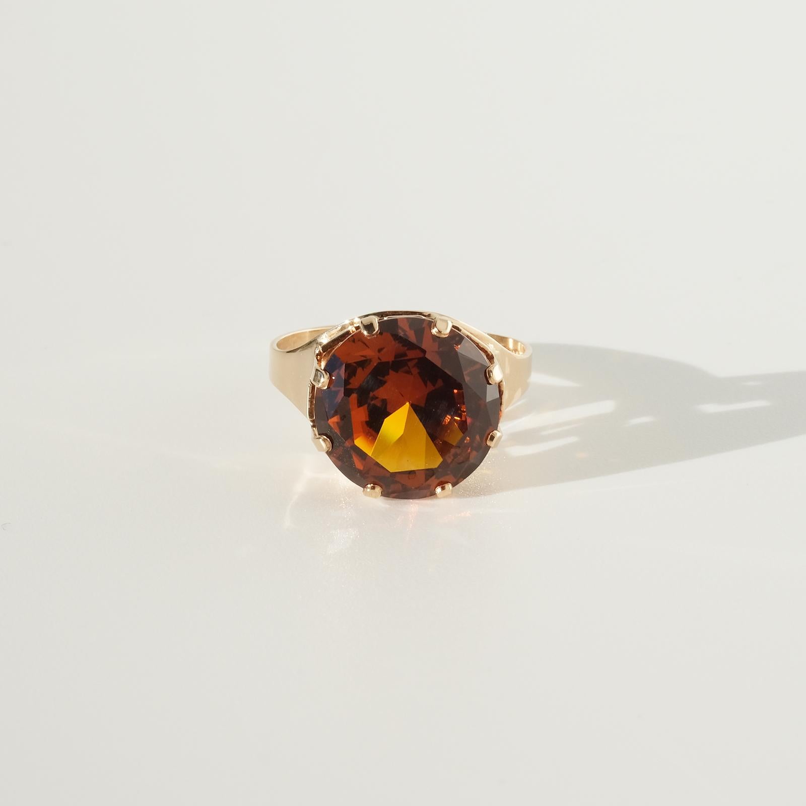 This 14 karat gold cocktail ring has a beautiful orange synthetic sapphire. The sapphire is hold by an amazing setting which resembles a king's crown. 

This ring is a perfect fit for the cocktail party, but it would of course also fit well in an