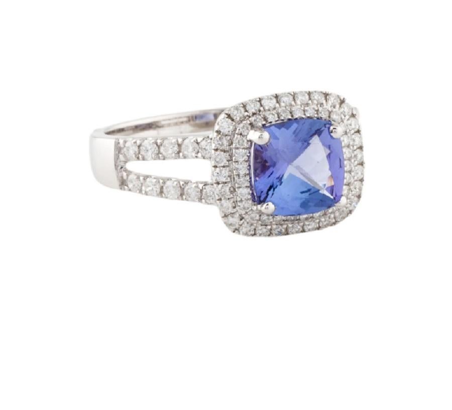 Il s'agit d'une superbe bague en tanzanite bleue et diamant blanc en or blanc 14K. De délicats diamants blancs encadrent les captivants diamants ronds de taille brillant, dont la tanzanite d'une excellente teinte bleue est mise en