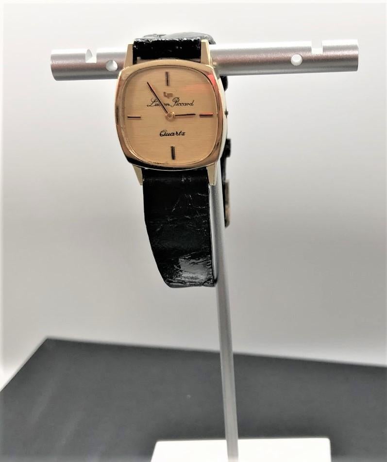14k yellow gold watch, dial signed Lucien Piccard with baton quarter hours, black leather band, length 8 inches.