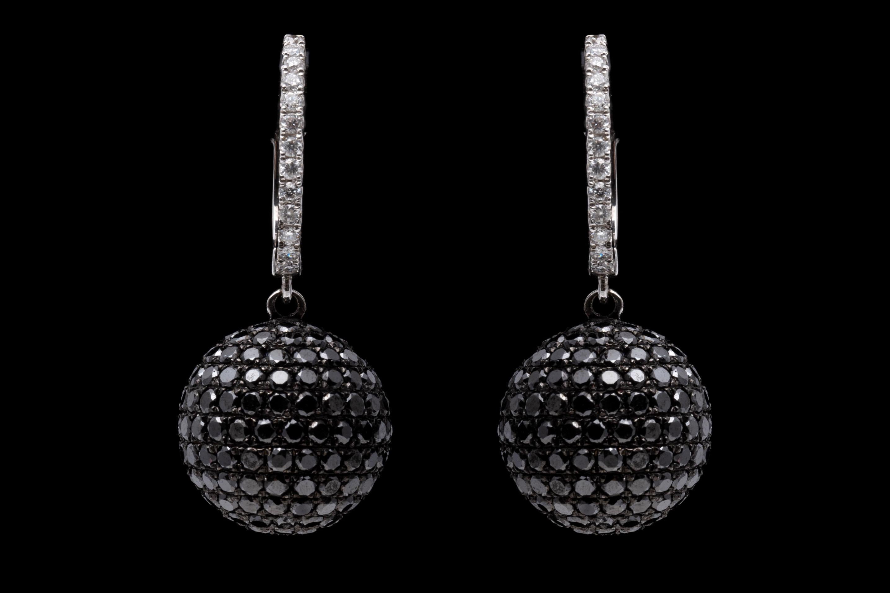 This ultra modern pair of 14K white gold earrings features a ball pendant pave set with black diamonds. White diamonds are set into the tops of the earrings complimenting the many black diamond creating a elegant appearance. Diamonds are