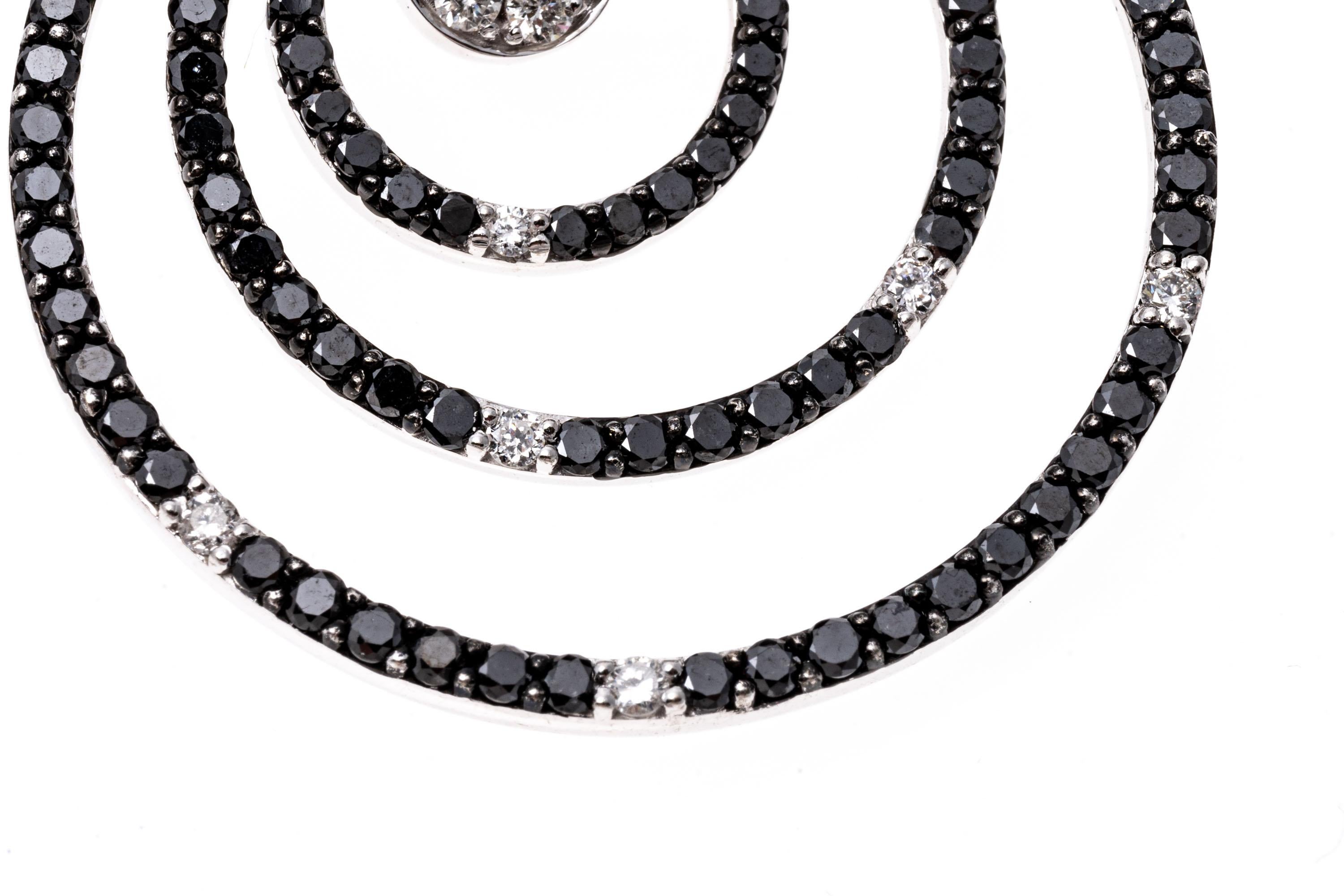 14k white gold earrings. These mod earrings contain a small round top, set with round faceted white diamonds; suspended from the top are three round concentric circles, set with black round faceted diamonds, prong set. Set within the center circle