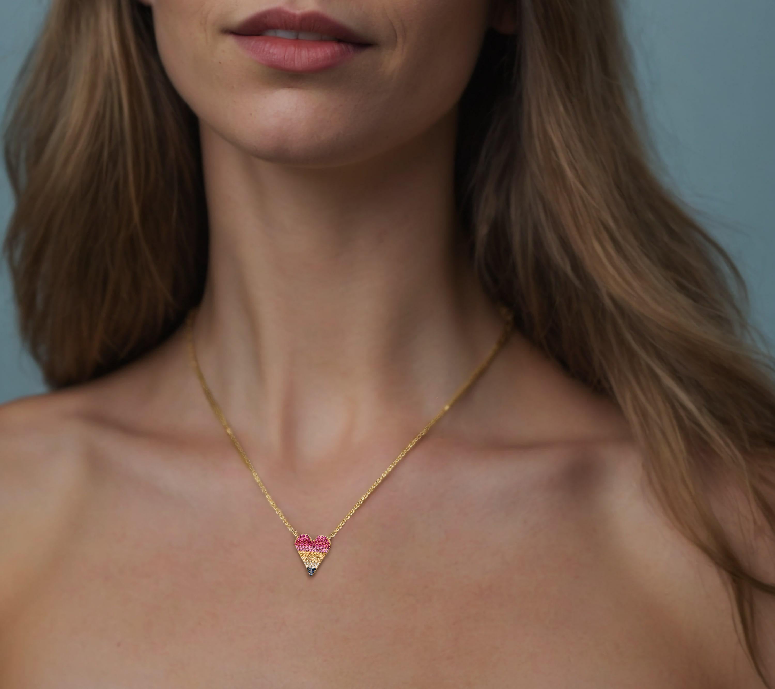 Aggiungi un tocco di eleganza e vivacità al tuo look con questa splendida collana Heart Pave in oro giallo 14K con diamanti e zaffiri multicolore. Questo splendido pezzo presenta un delicato ciondolo a forma di cuore ornato da una serie di gemme