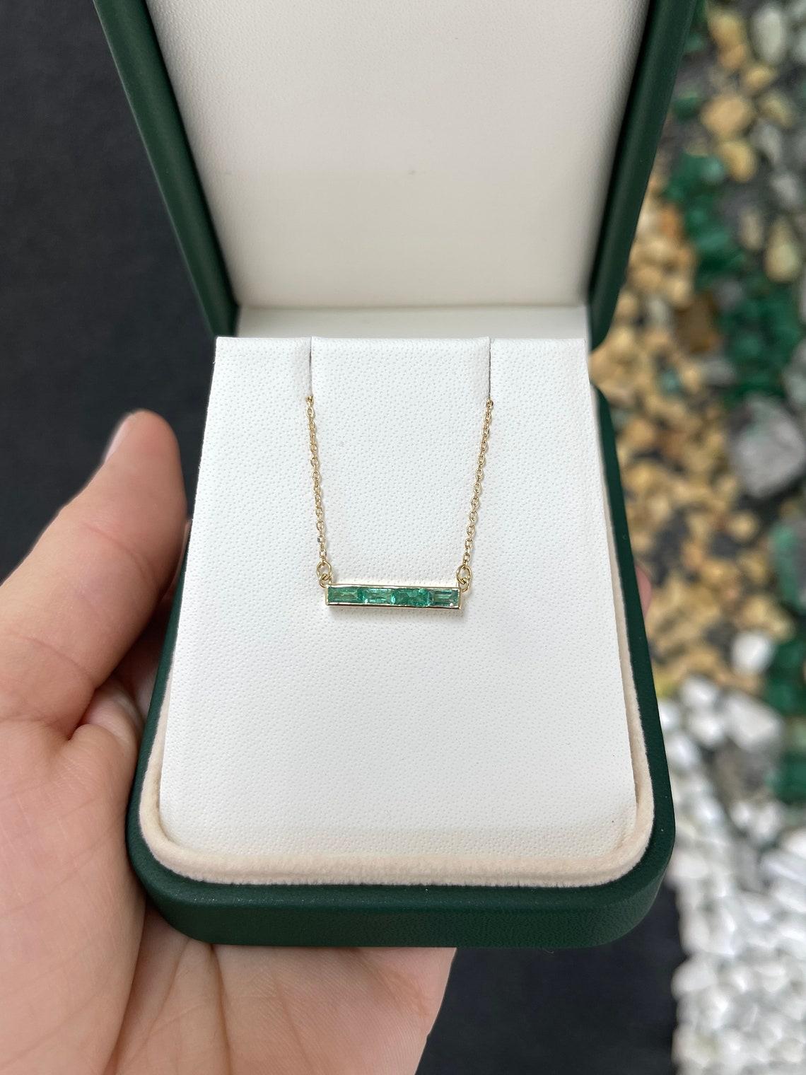 Questa splendida collana a barretta in oro 14k mette in mostra quattro squisiti smeraldi naturali tagliati a baguette, che vantano una tonalità verde media, una chiarezza semitrasparente e una lucentezza accattivante, per un totale di 0,60 carati.