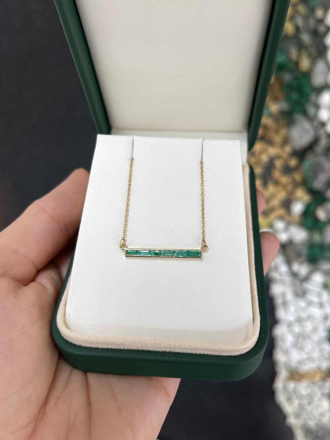 Diese atemberaubende 14-karätige Goldkette präsentiert vier exquisite natürliche Smaragde im Baguetteschliff mit einem mittelgrünen Farbton, halbtransparenter Klarheit und fesselndem Glanz von insgesamt 0,90 Karat. Die Smaragde sind fachmännisch von